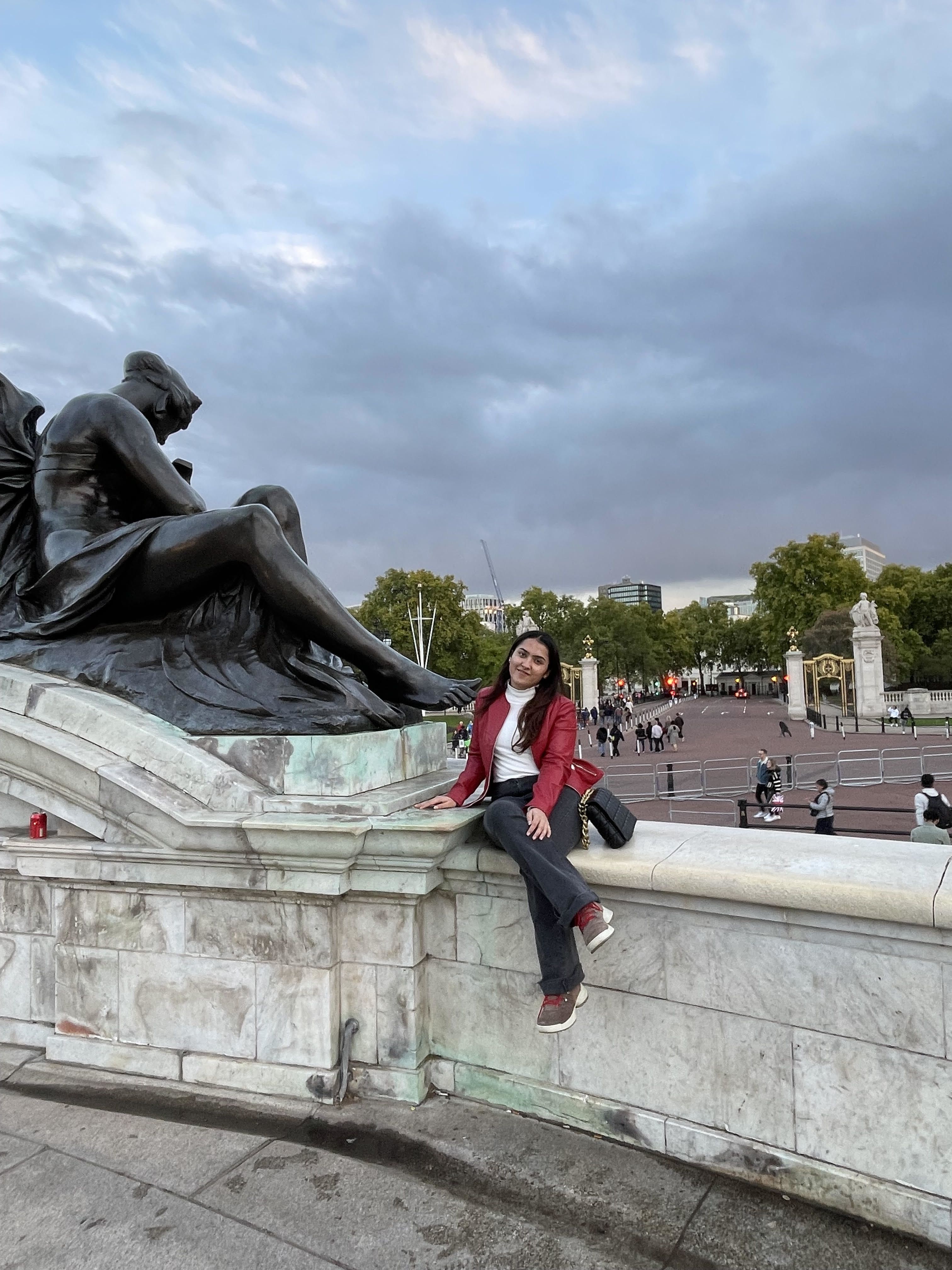 Ashima sitting on a wall outside Buckingham Palace, London