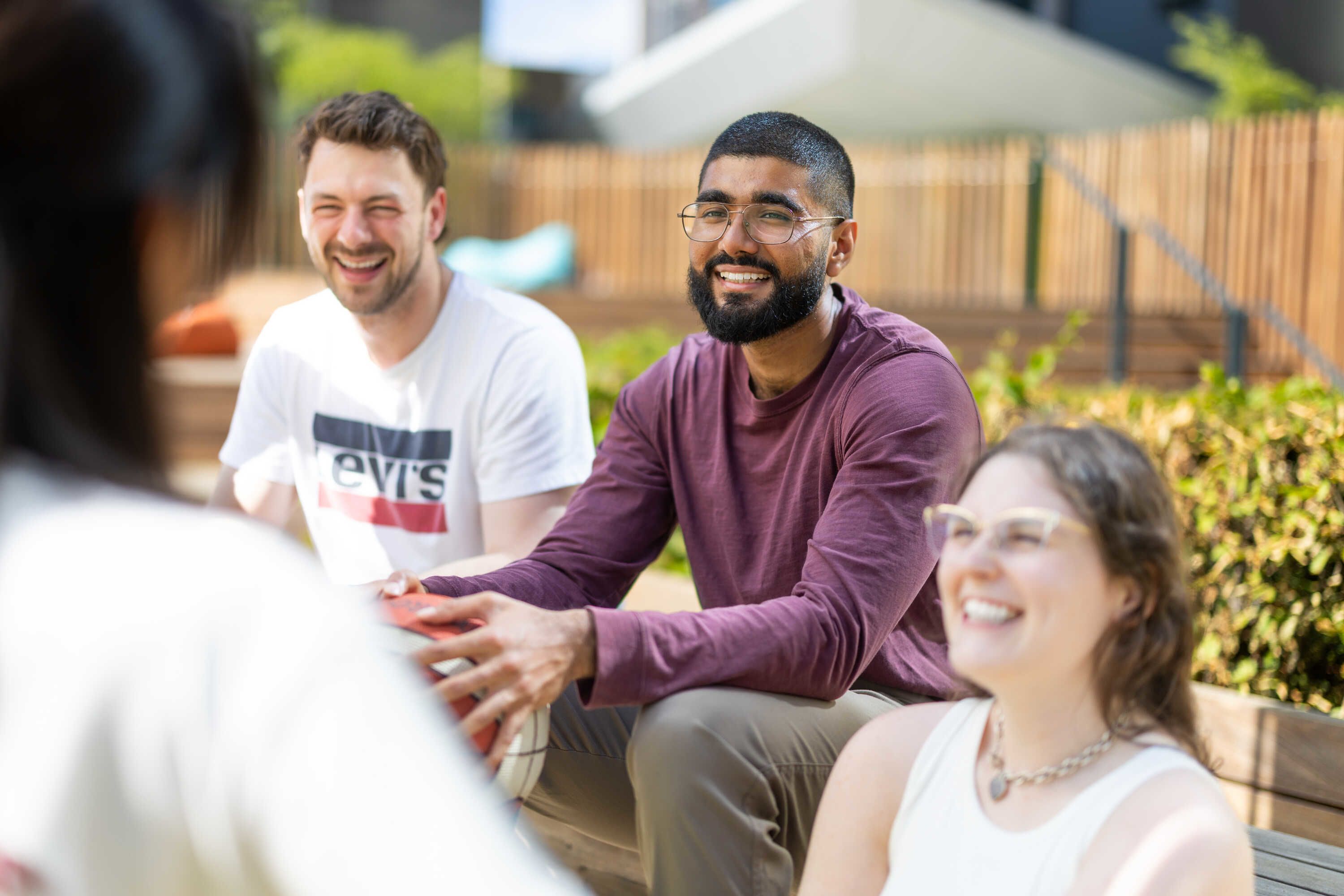 Haaris chatting with friends on an outdoor bench