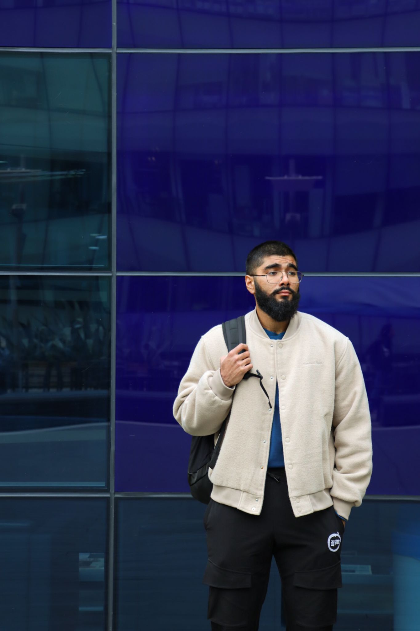 Haaris standing in front of a blue glass wall