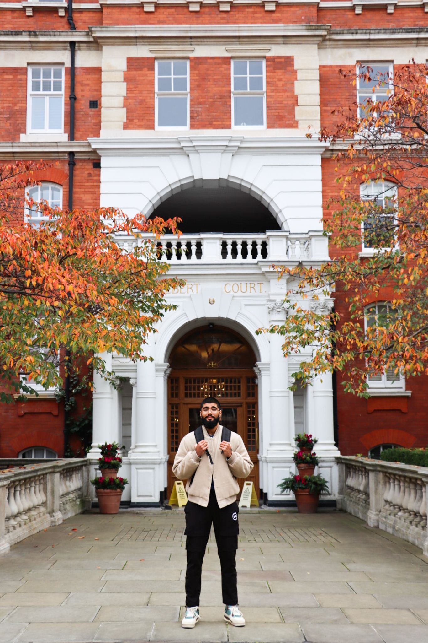 Haaris standing outside Albert Court with autumn leaves on the trees in the background