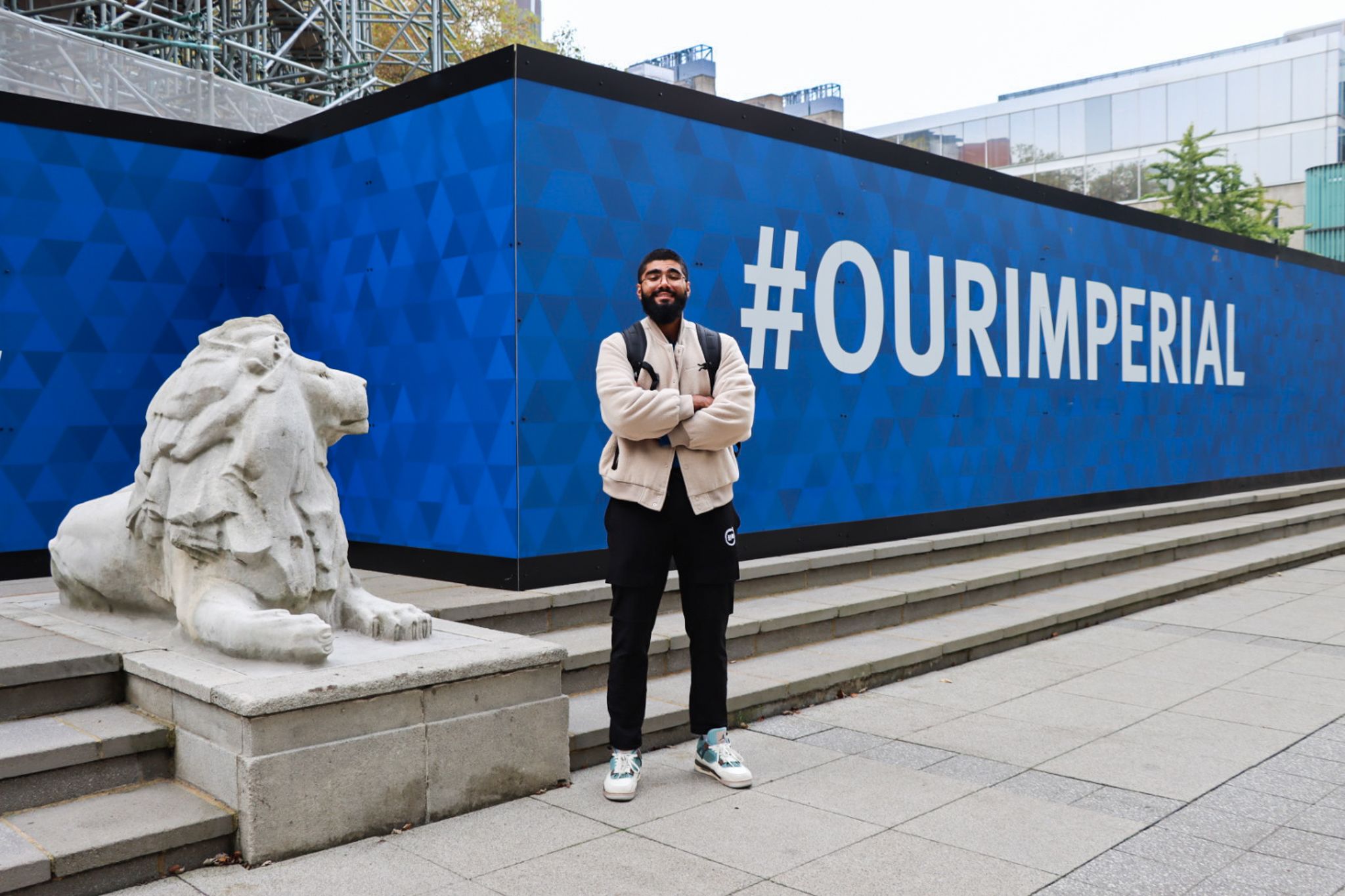 Haaris standing next to a lion statue and in front of a billboard saying #OurImperial