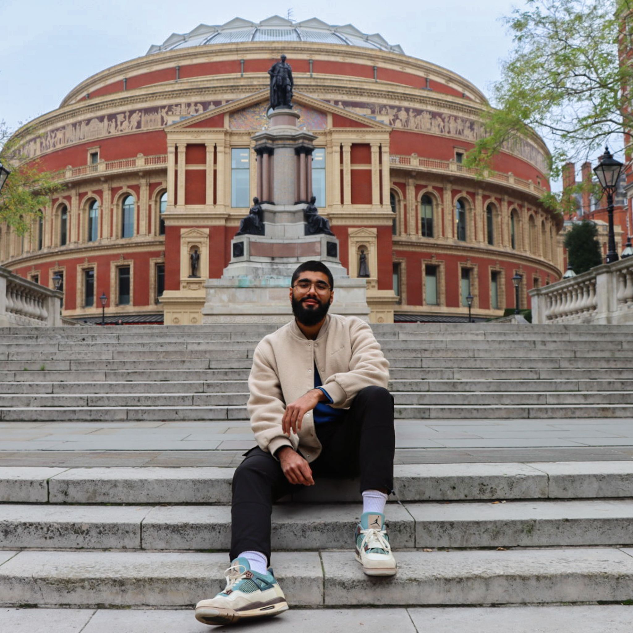 Haaris smiling at camera while sitting on the stairs outside Royal Albert Hall
