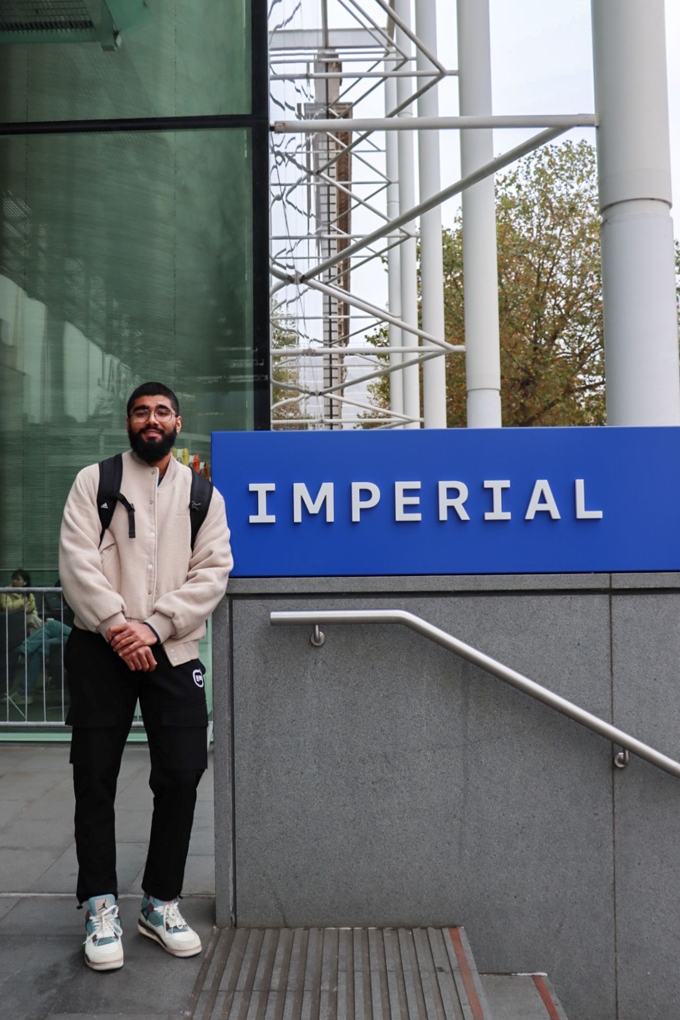 Haaris standing by the South Kensington Campus main entrance staircase with a small Imperial logo