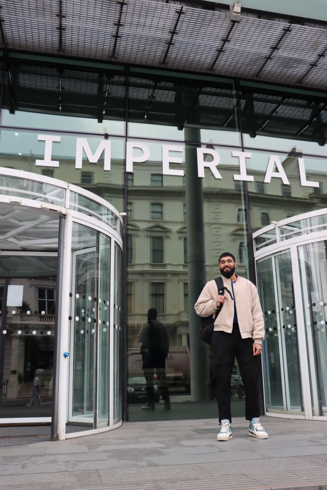 Haaris standing outside the main entrance of South Kensington Campus, with the Imperial logo above him
