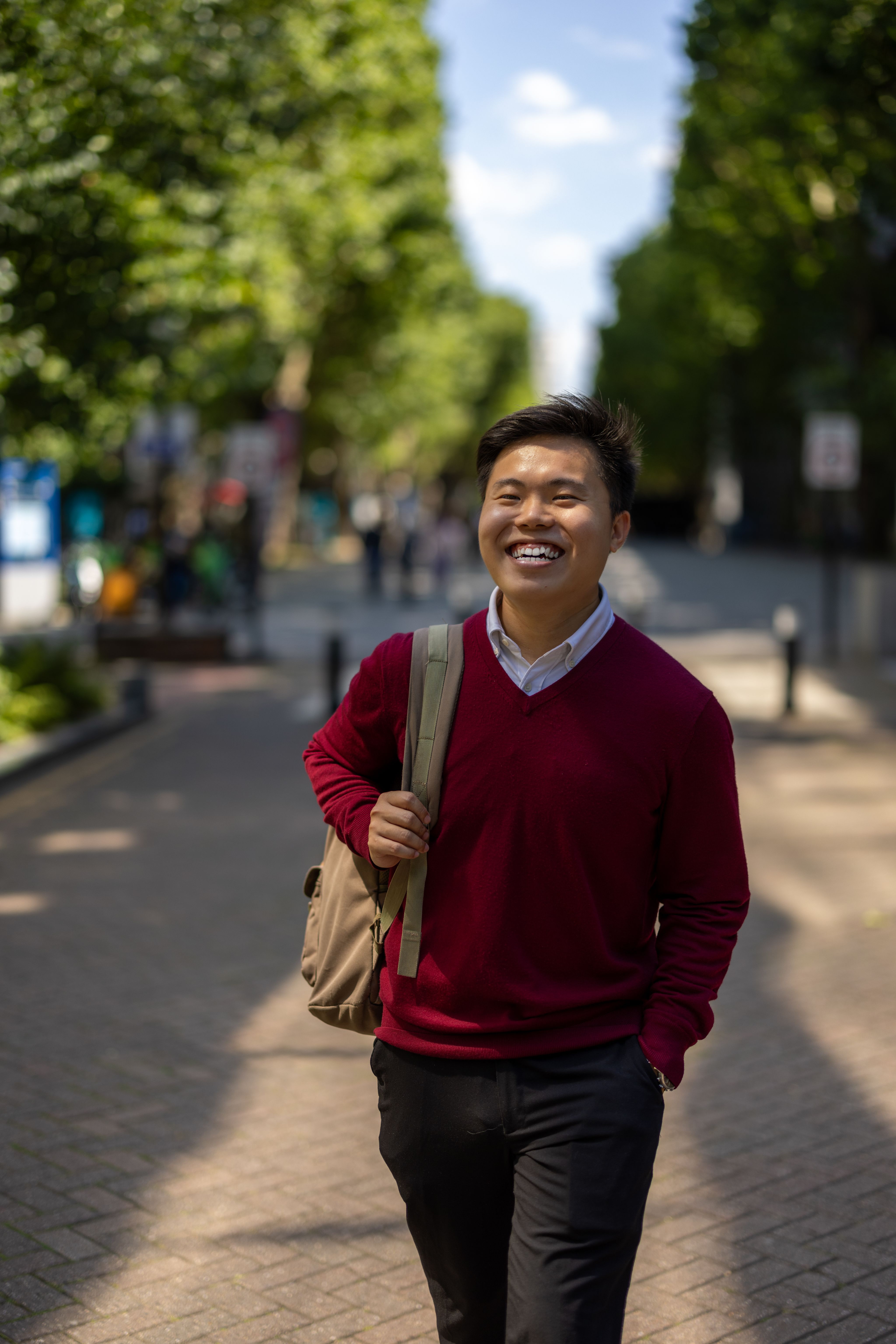 Han Ming holding a backpack on one shoulder walking through South Kensington Campus