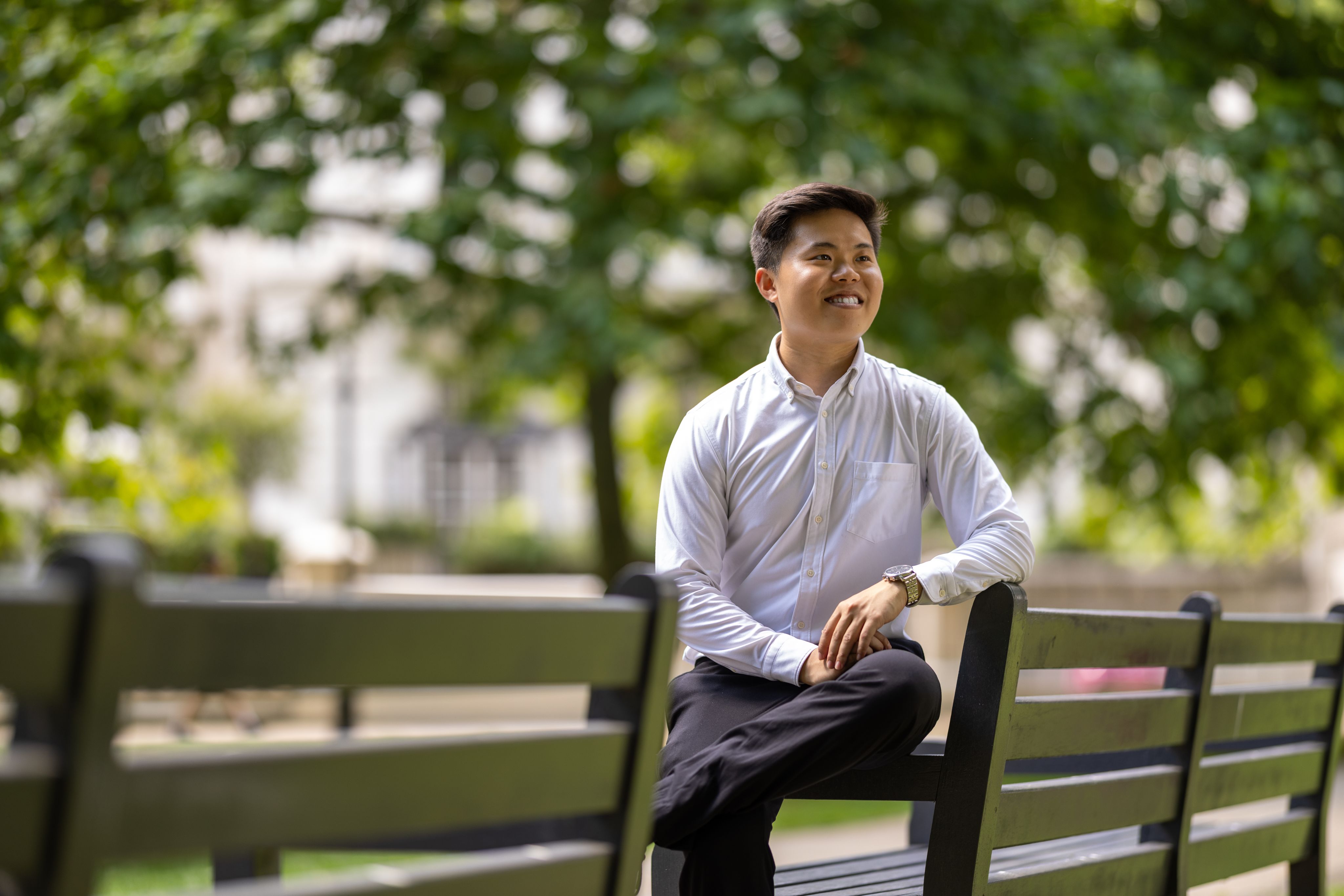 Han Ming sitting on a bench in Prince's Gardens on South Kensington Campus