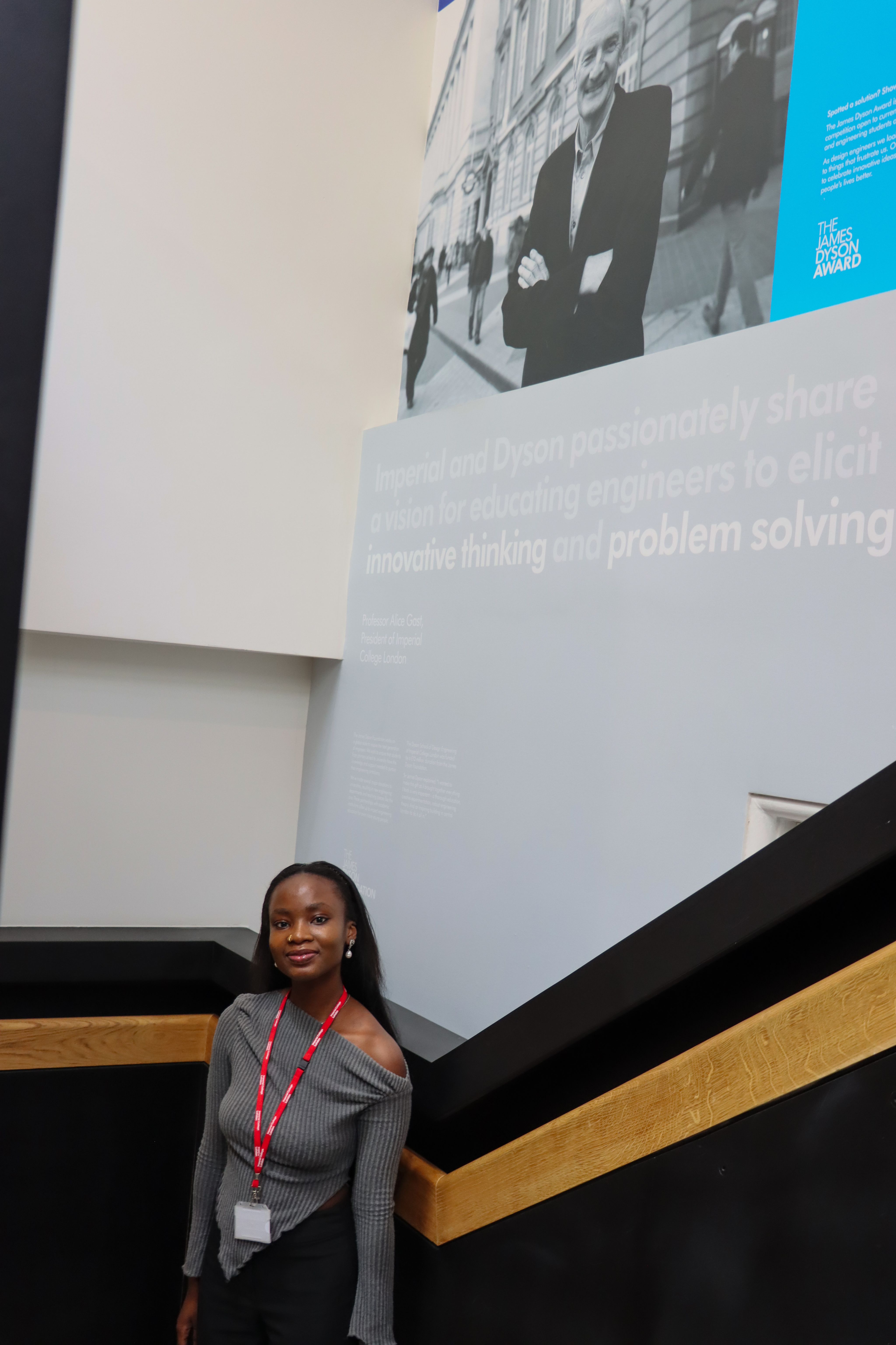 Ifeoluwa standing in front of a print on the wall, with words saying 'innovative thinking and problem solving' visible