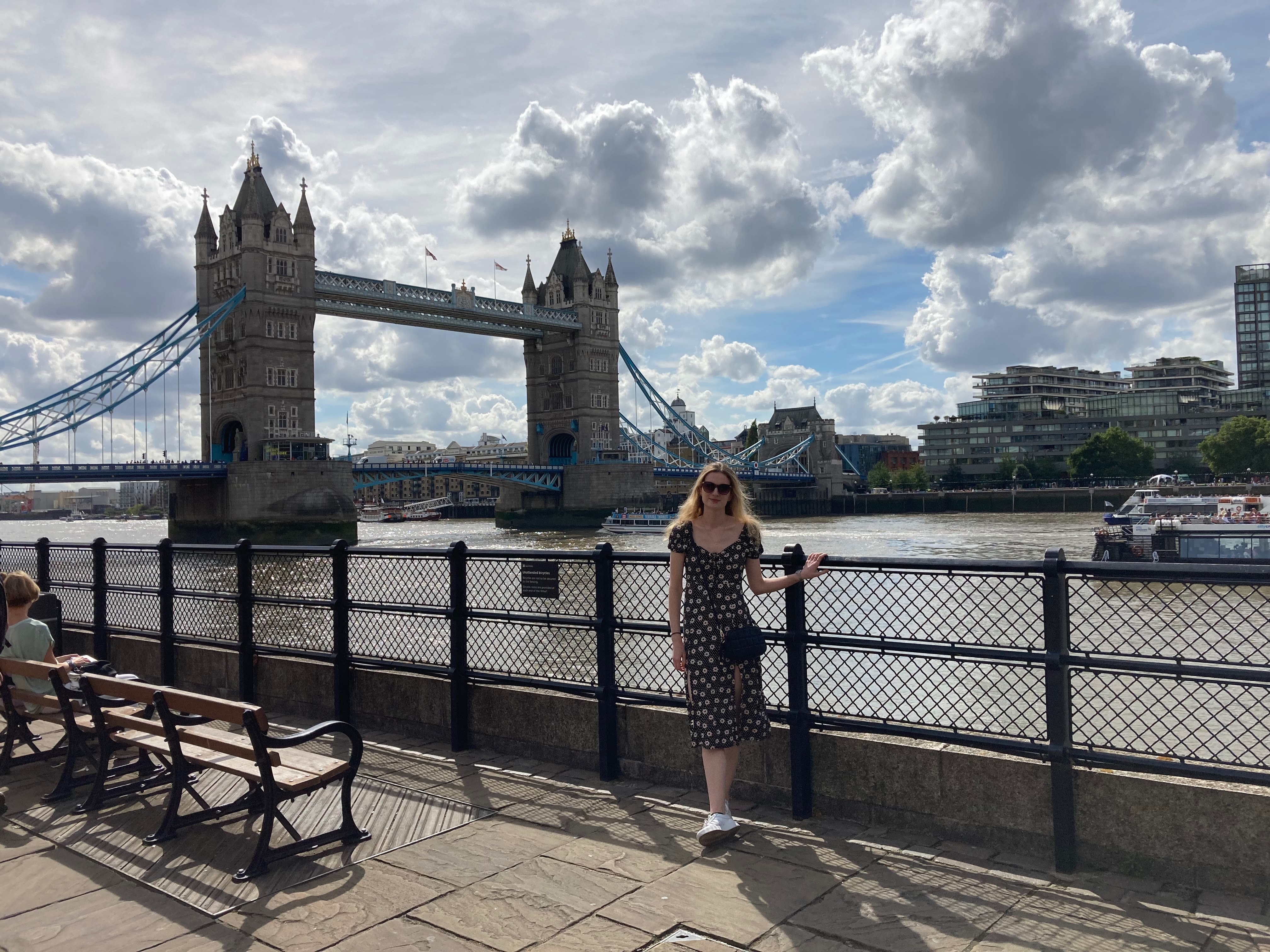 Katie on a sunny day wearing sunglasses posing in front of Tower Bridge in London