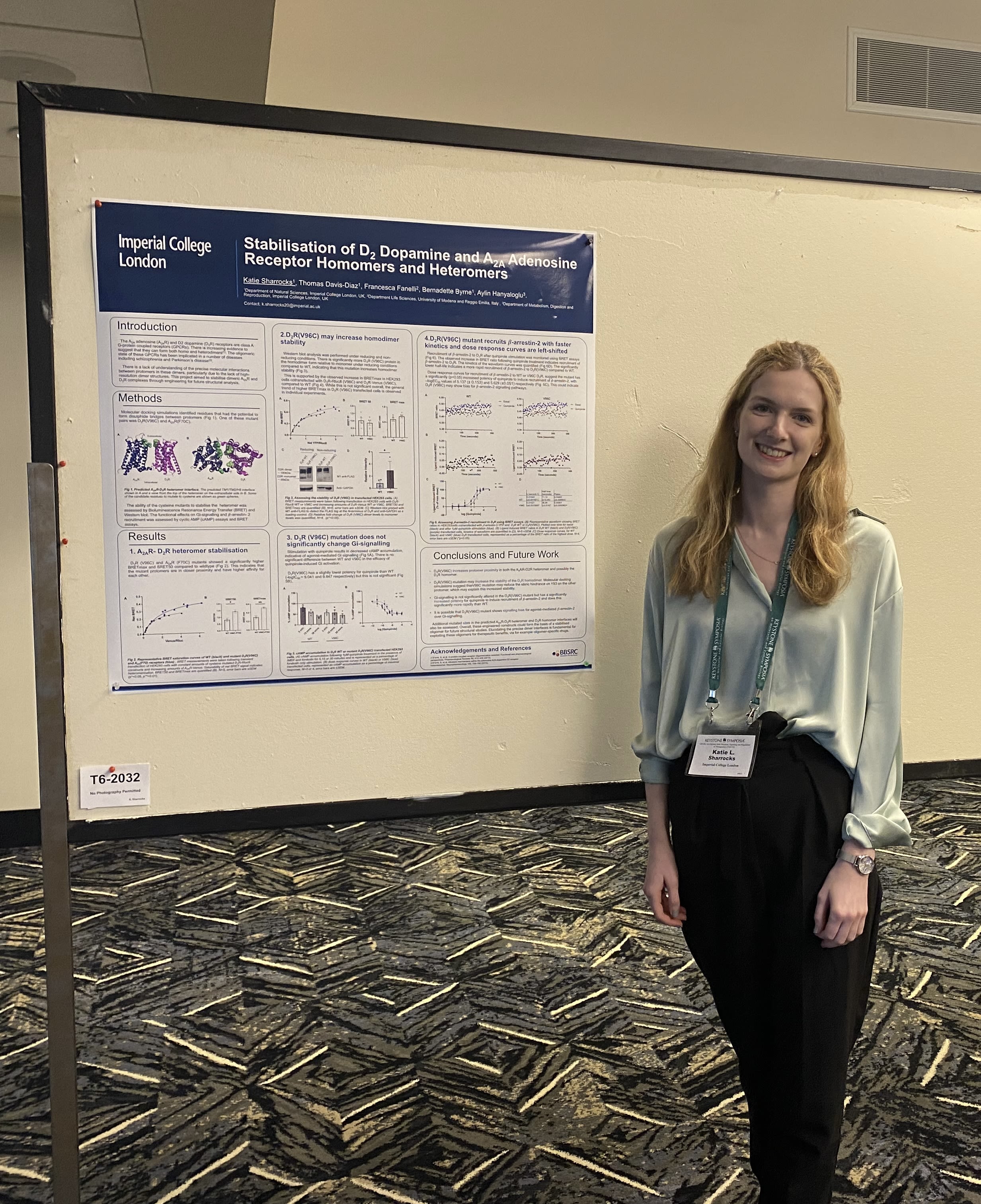 Katie standing in front of a poster showcasing some of her work