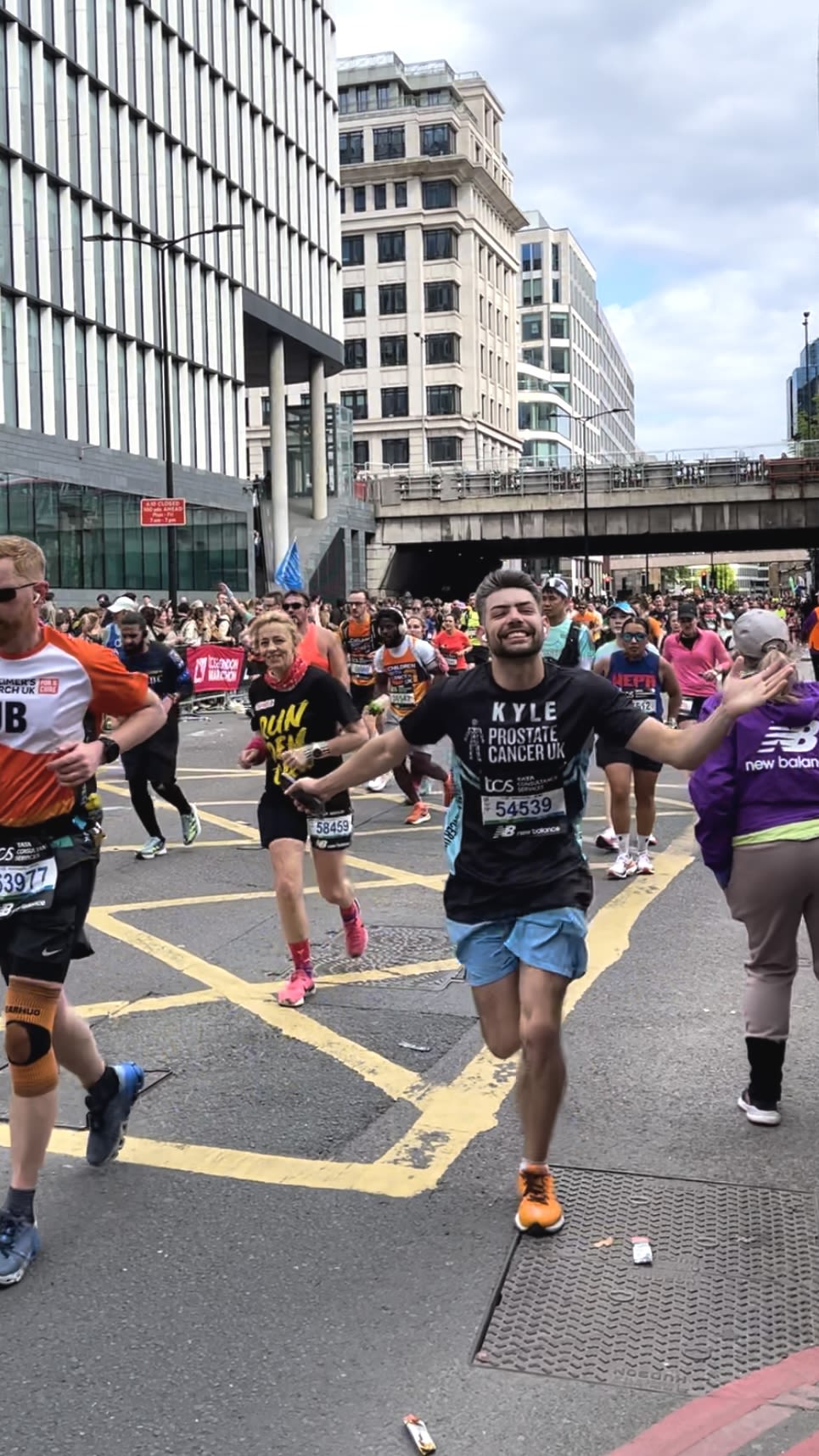 Kyle smiling at the camera while running in a big group of people