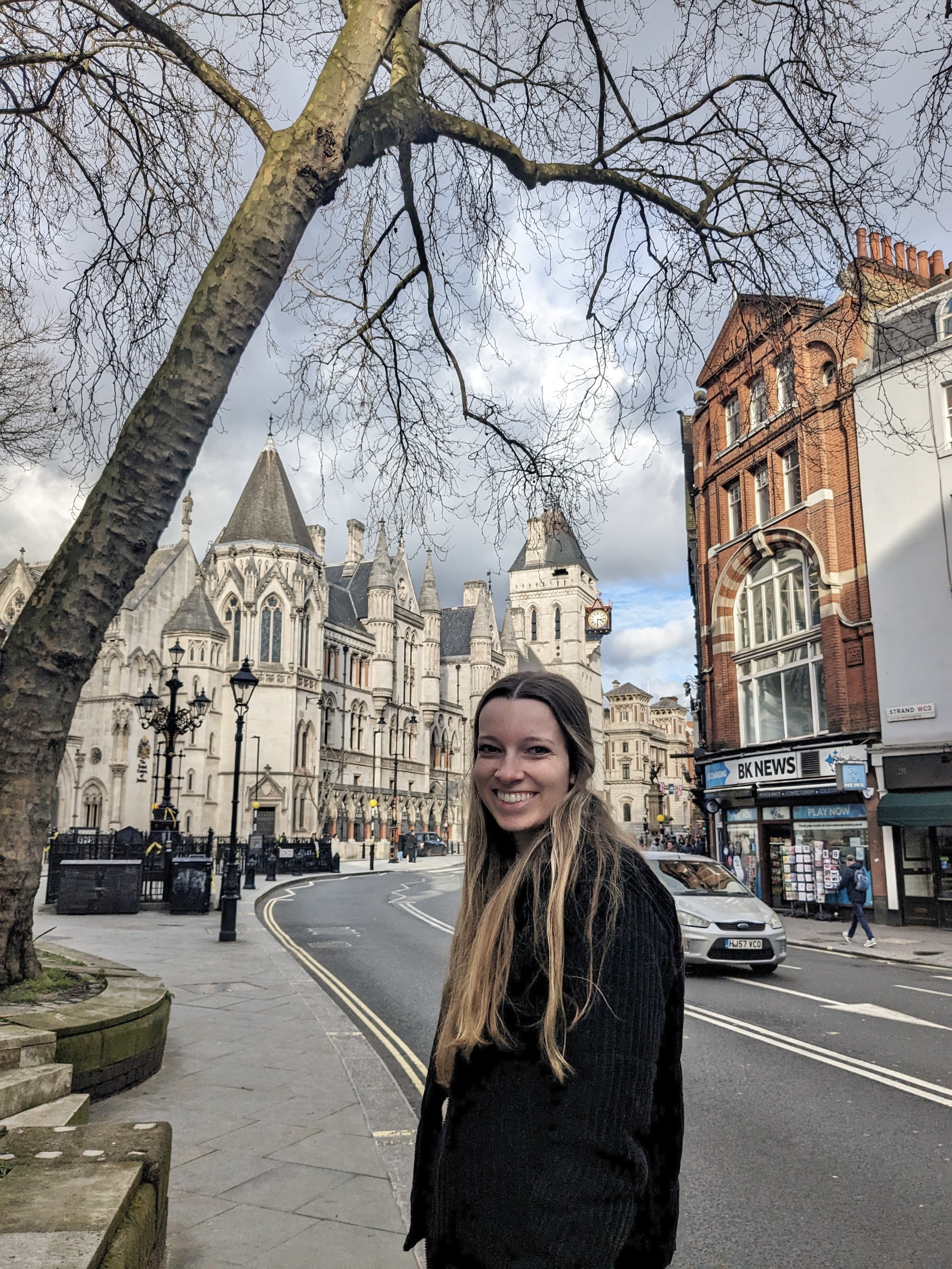 McKenna standing on a picturesque road in London, with old buildings in the background