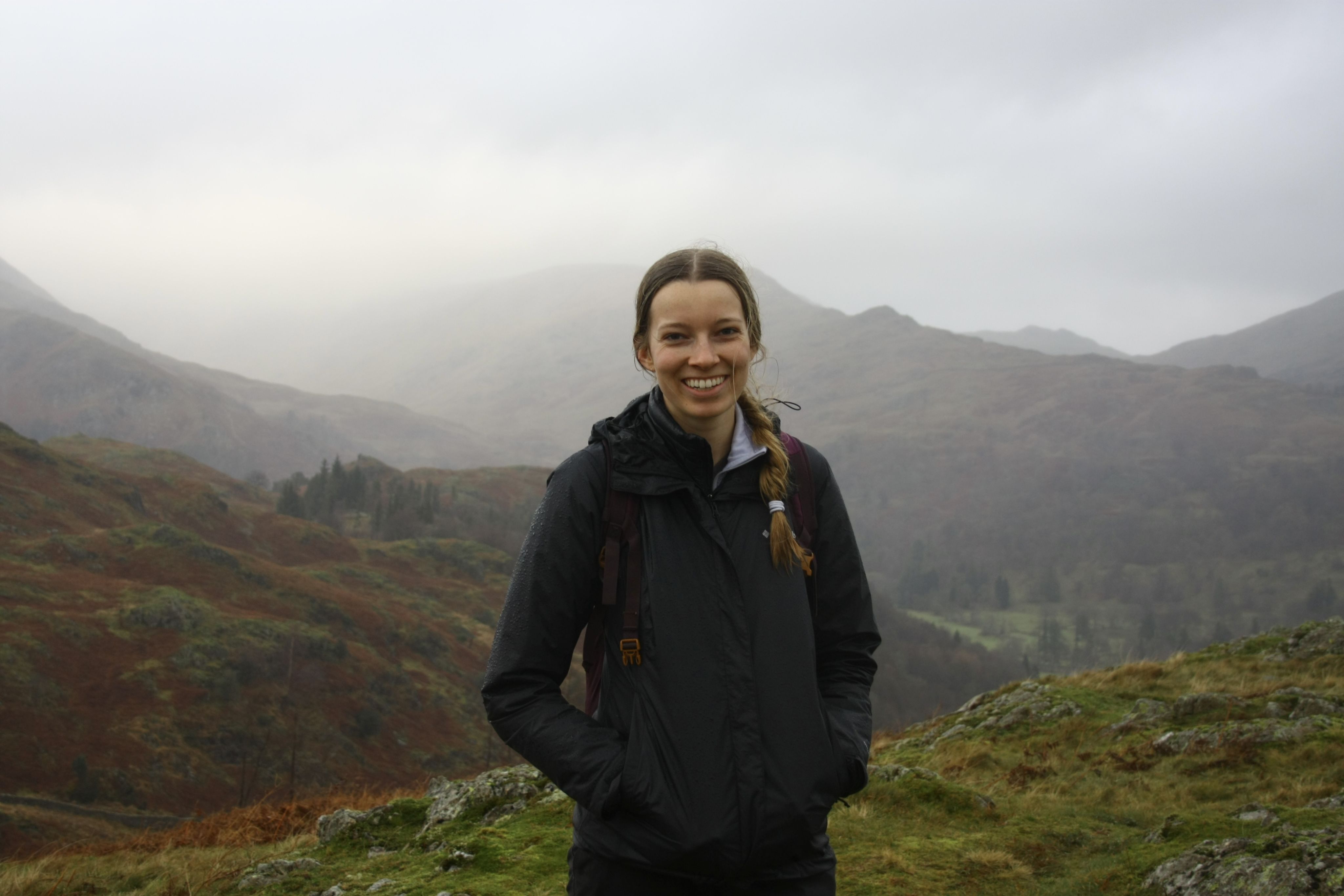 McKenna standing outdoors in front of some mountains covered in fog