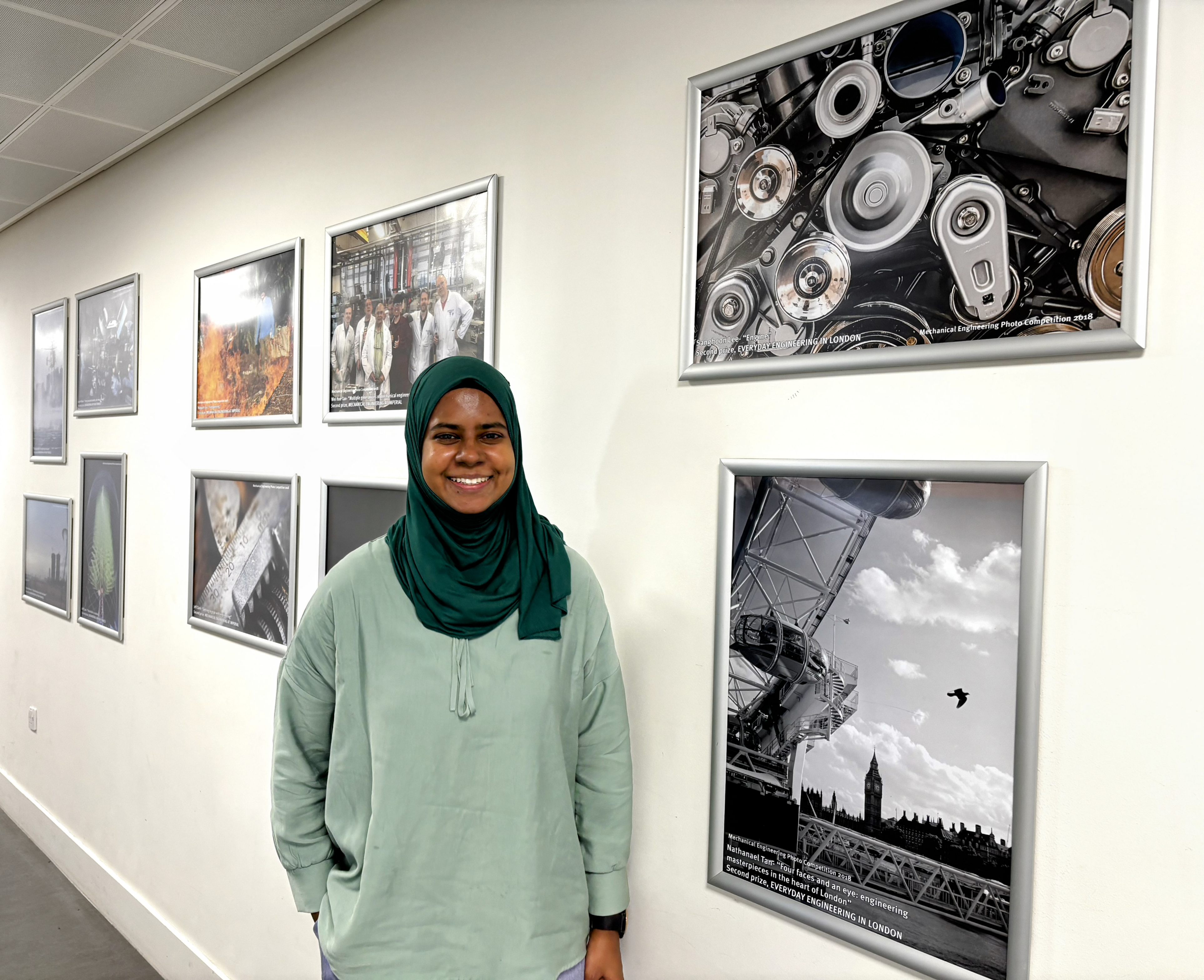 Nafisah standing next to environmental technology-related framed photographs on a wall