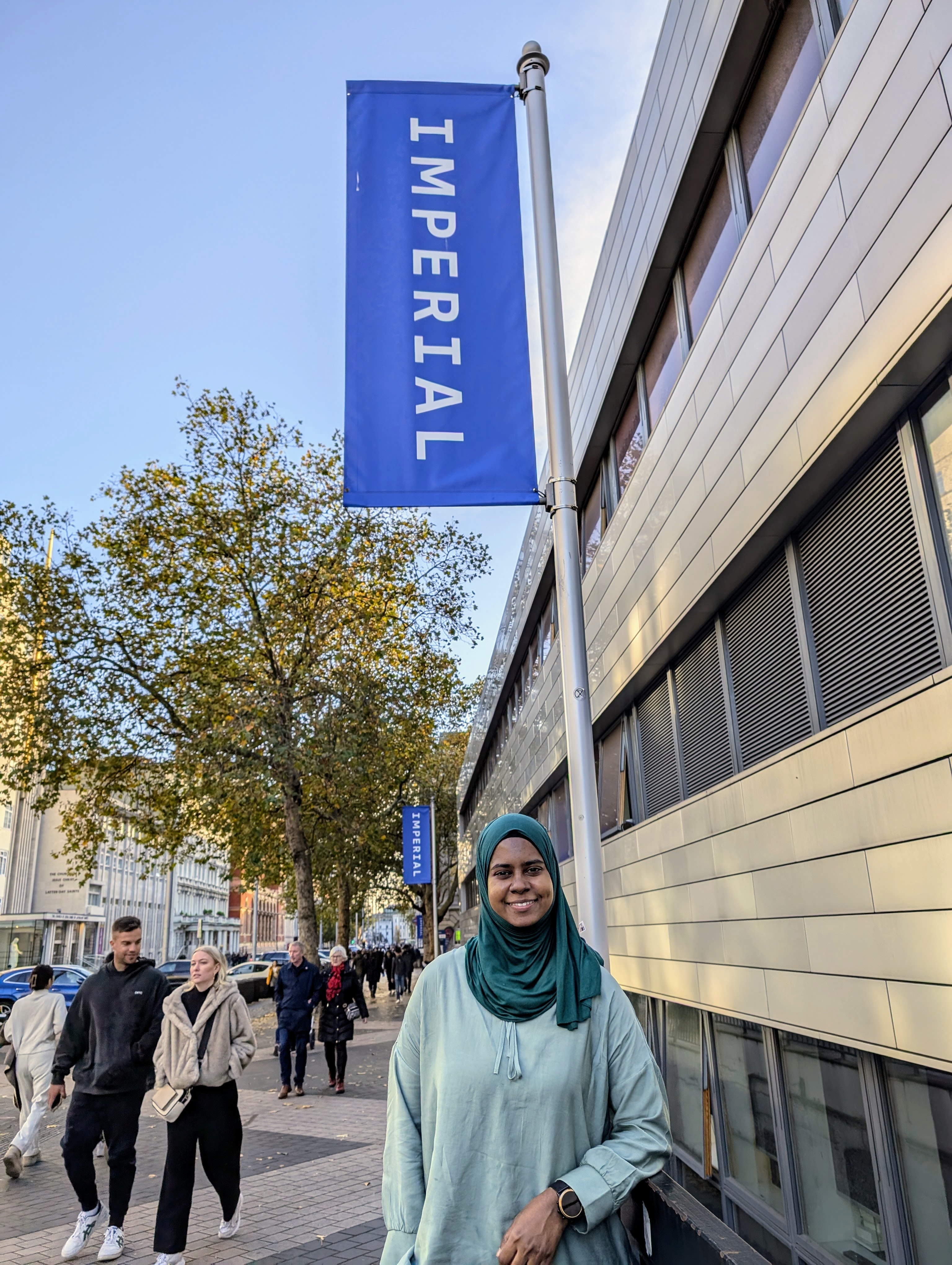 Nafisah standing underneath a flag banner with the Imperial banner