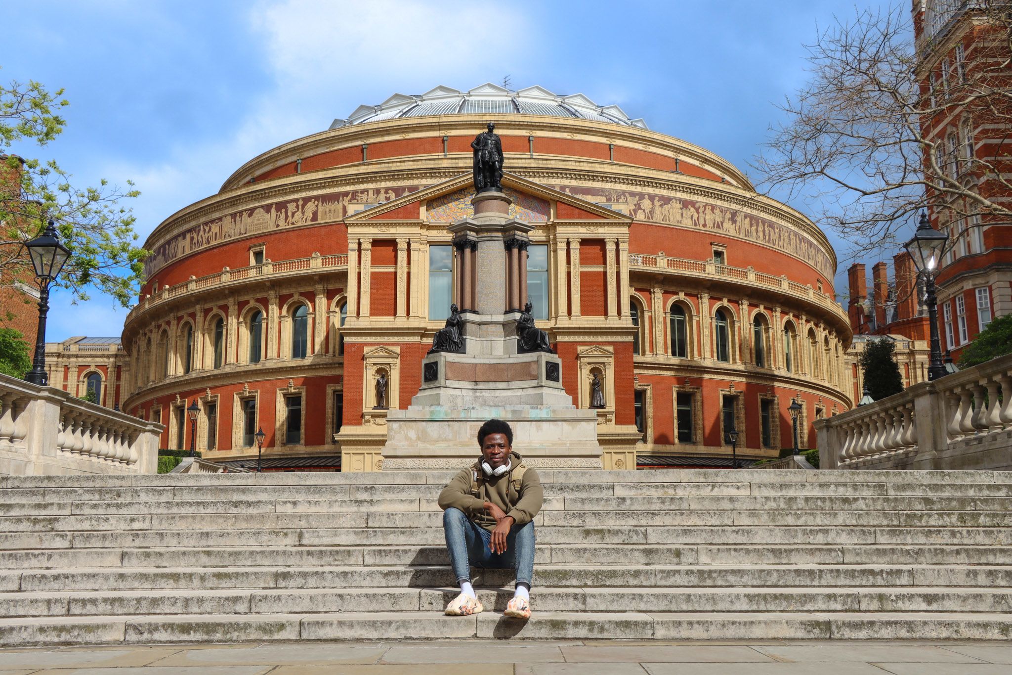 Oluwafemi sitting on some steps with the Royal Albert Hall behind him