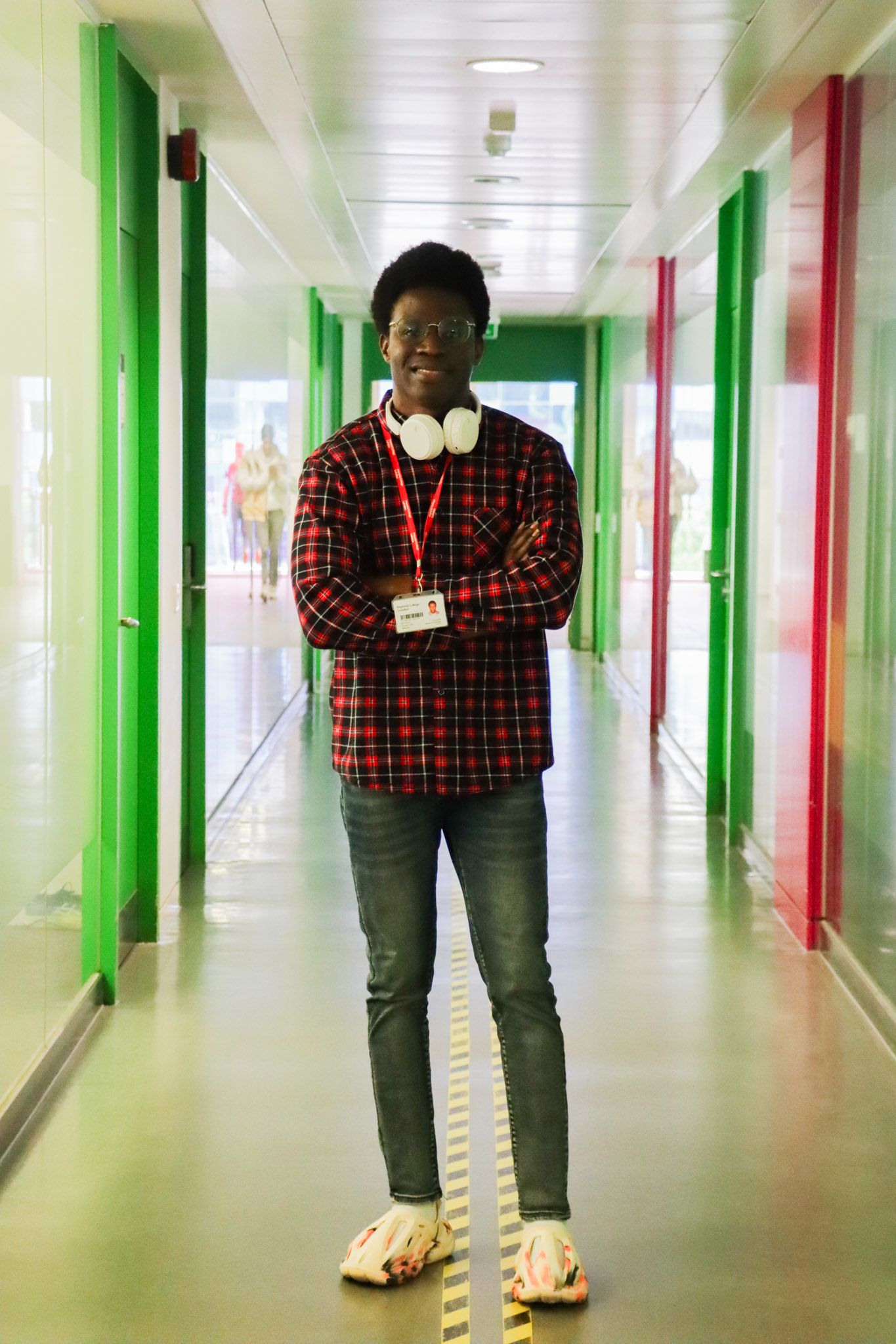 Oluwafemi posing in the middle of a corridor with colourful green and red designs on the walls