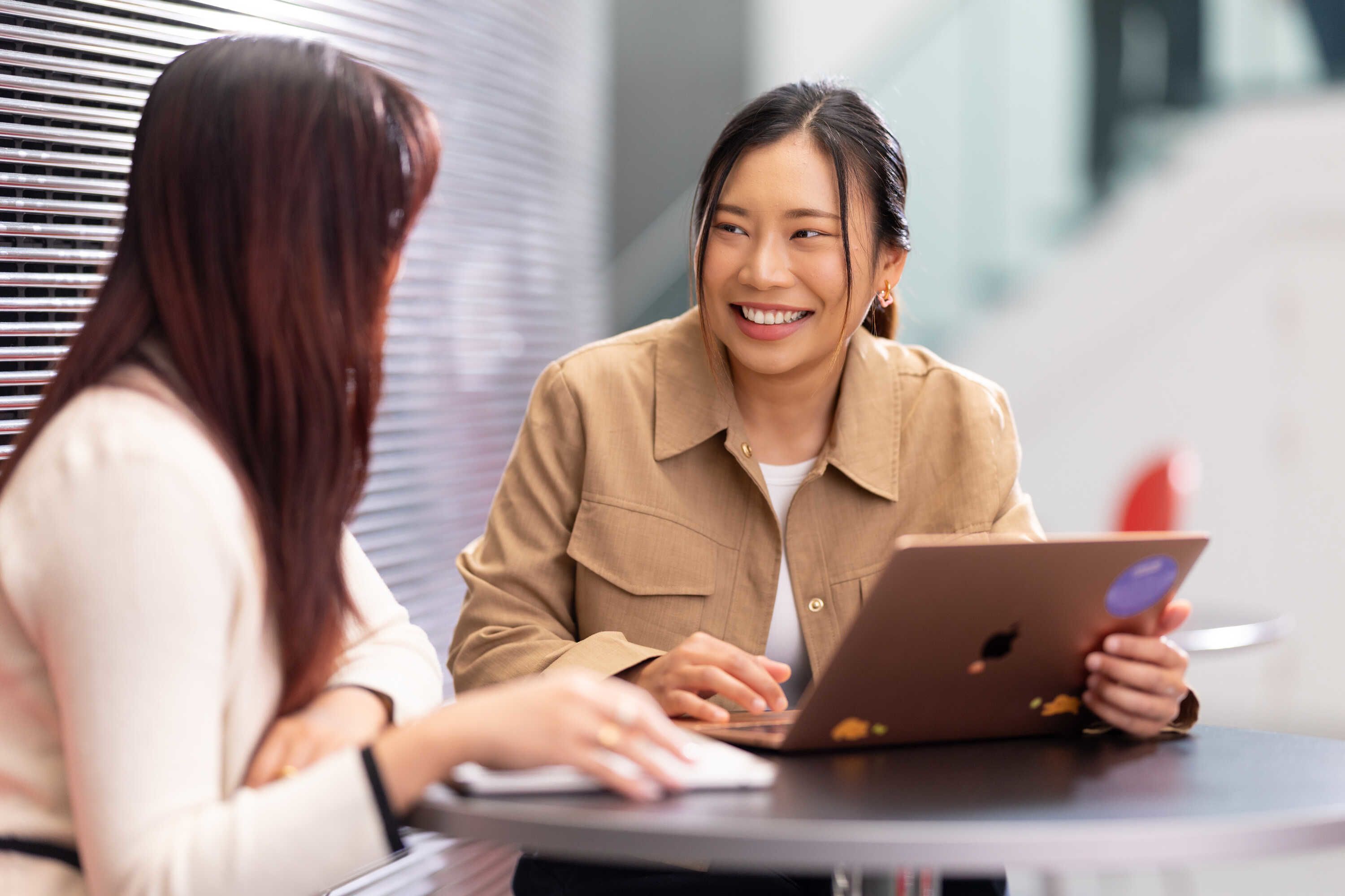 Rose smiling at a friend while working on a laptop