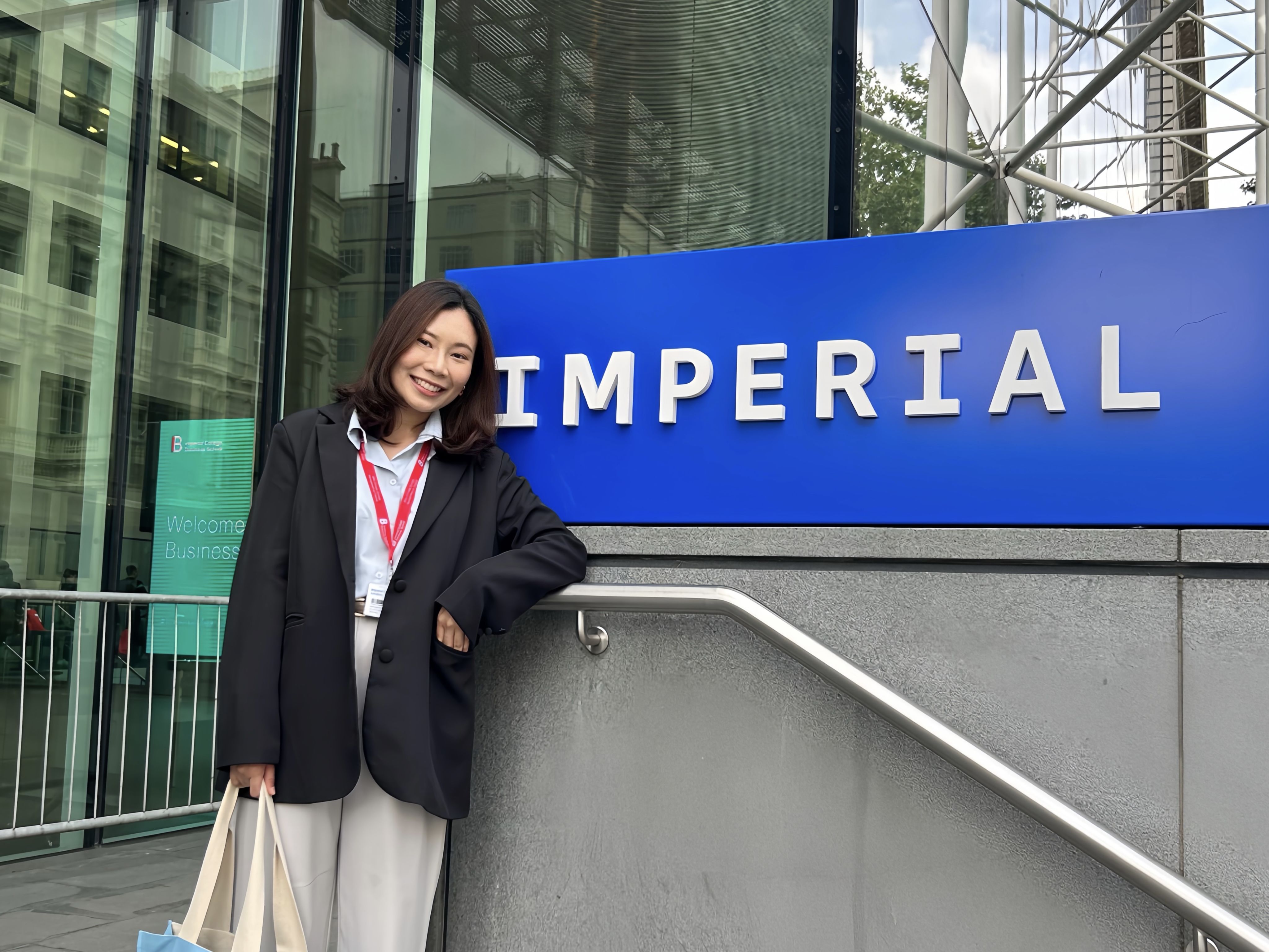 Rose standing with the Imperial logo by the main entrance on South Kensington Campus