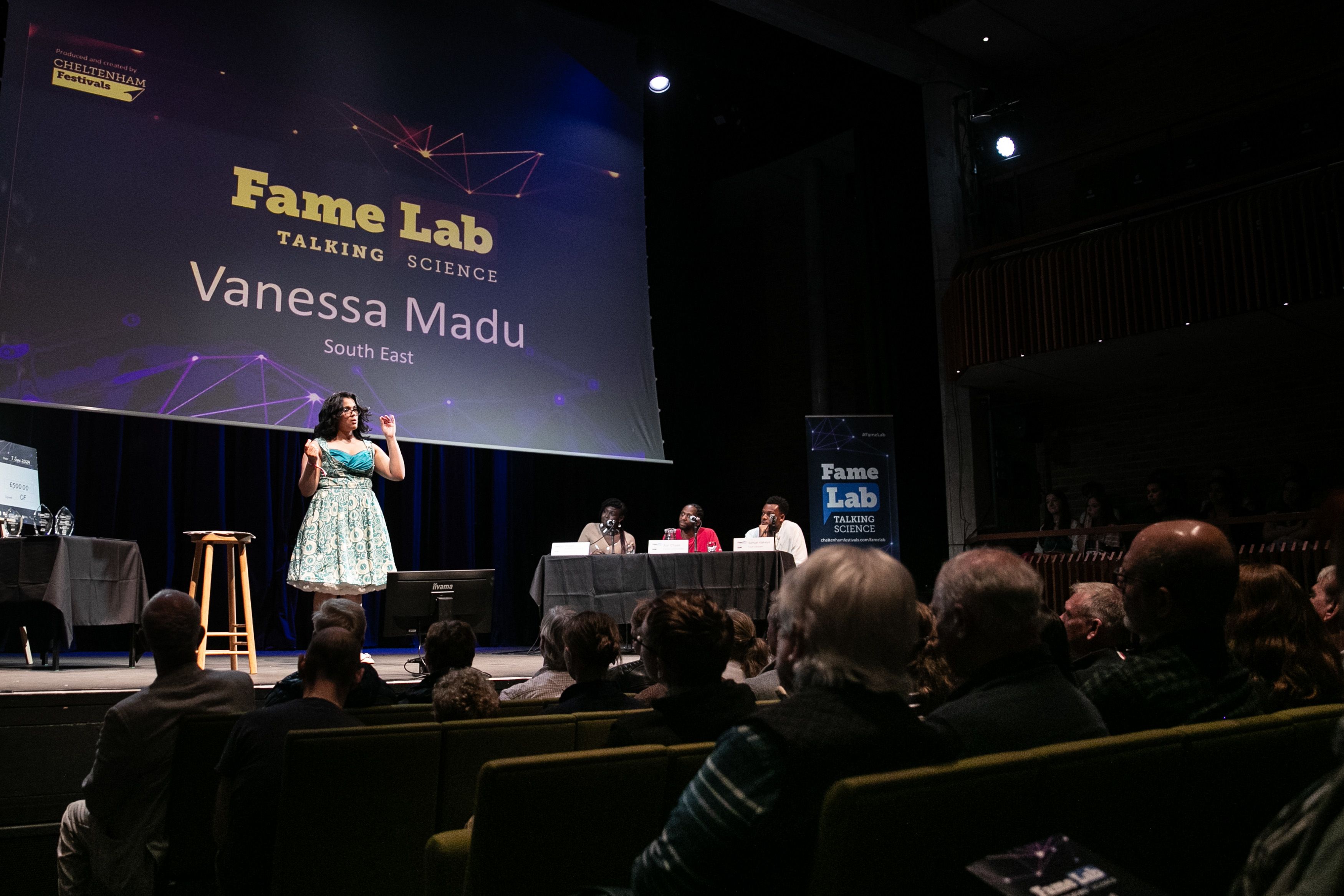 Vanessa on stage giving a talk at a Fame Lab event