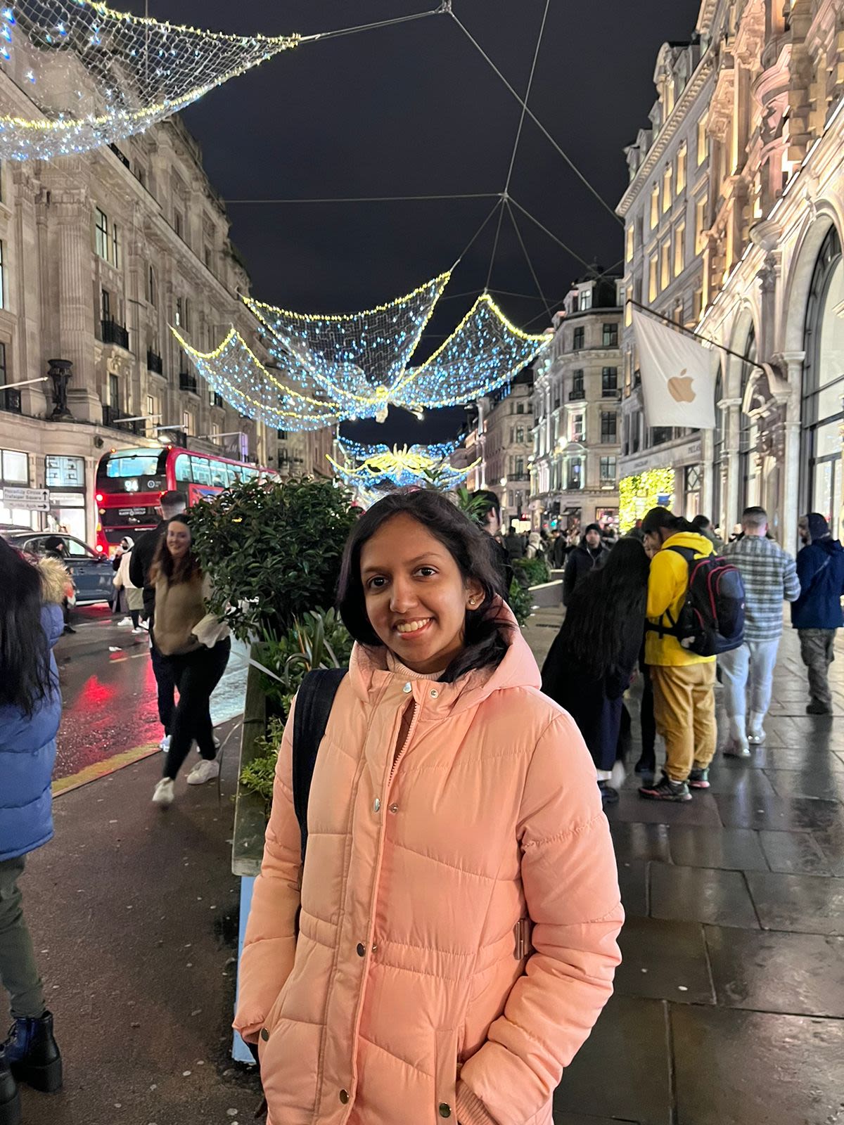 Vanya standing in front of decorative lights on a street in London at night
