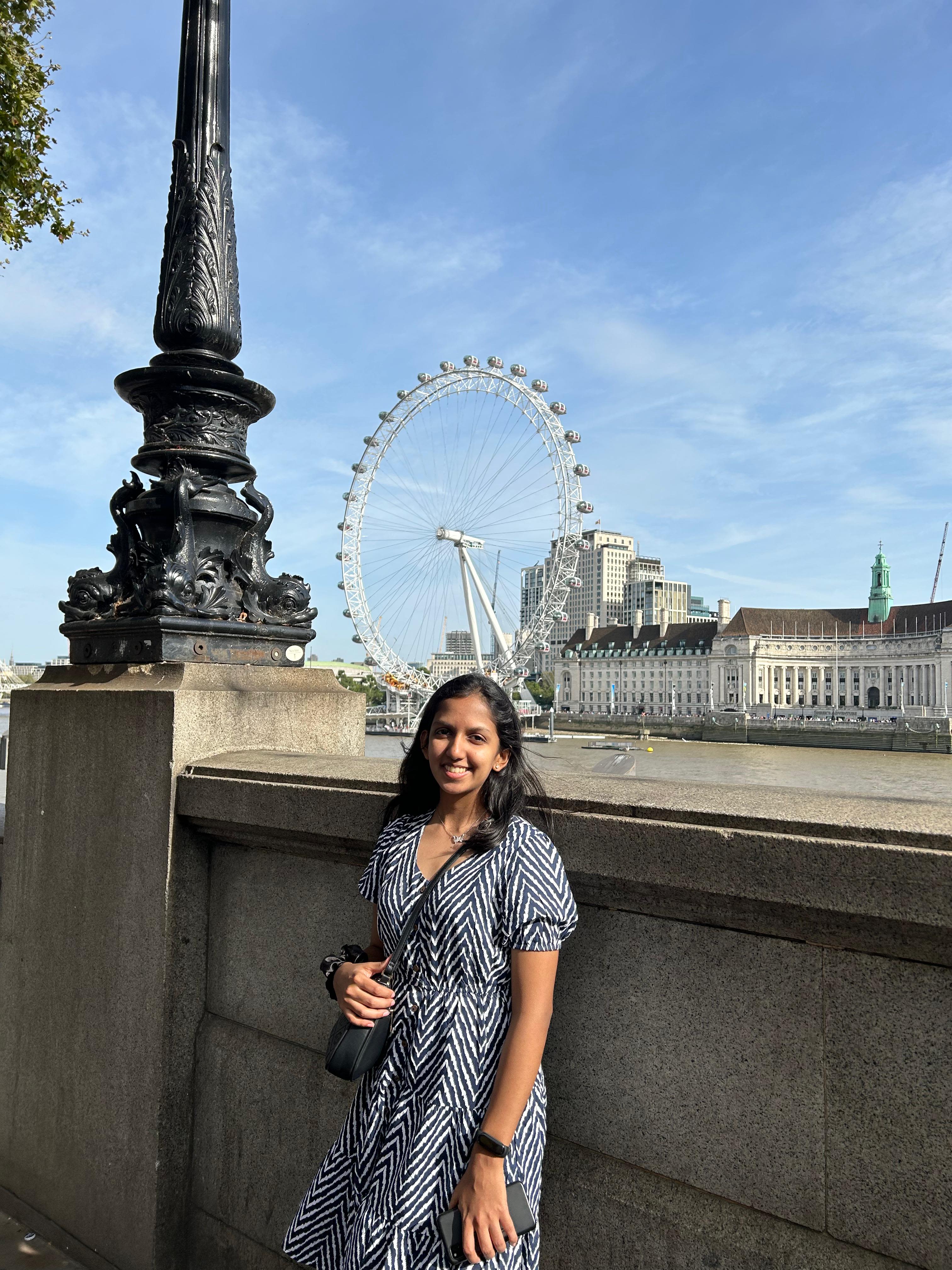 Vanya standing in front of the London Eye on a sunny day