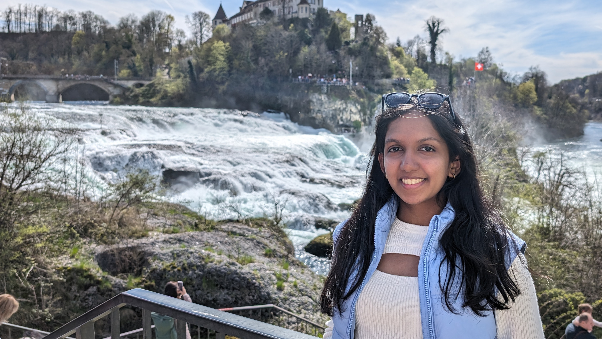 Vanya standing in front of a waterfall while travelling
