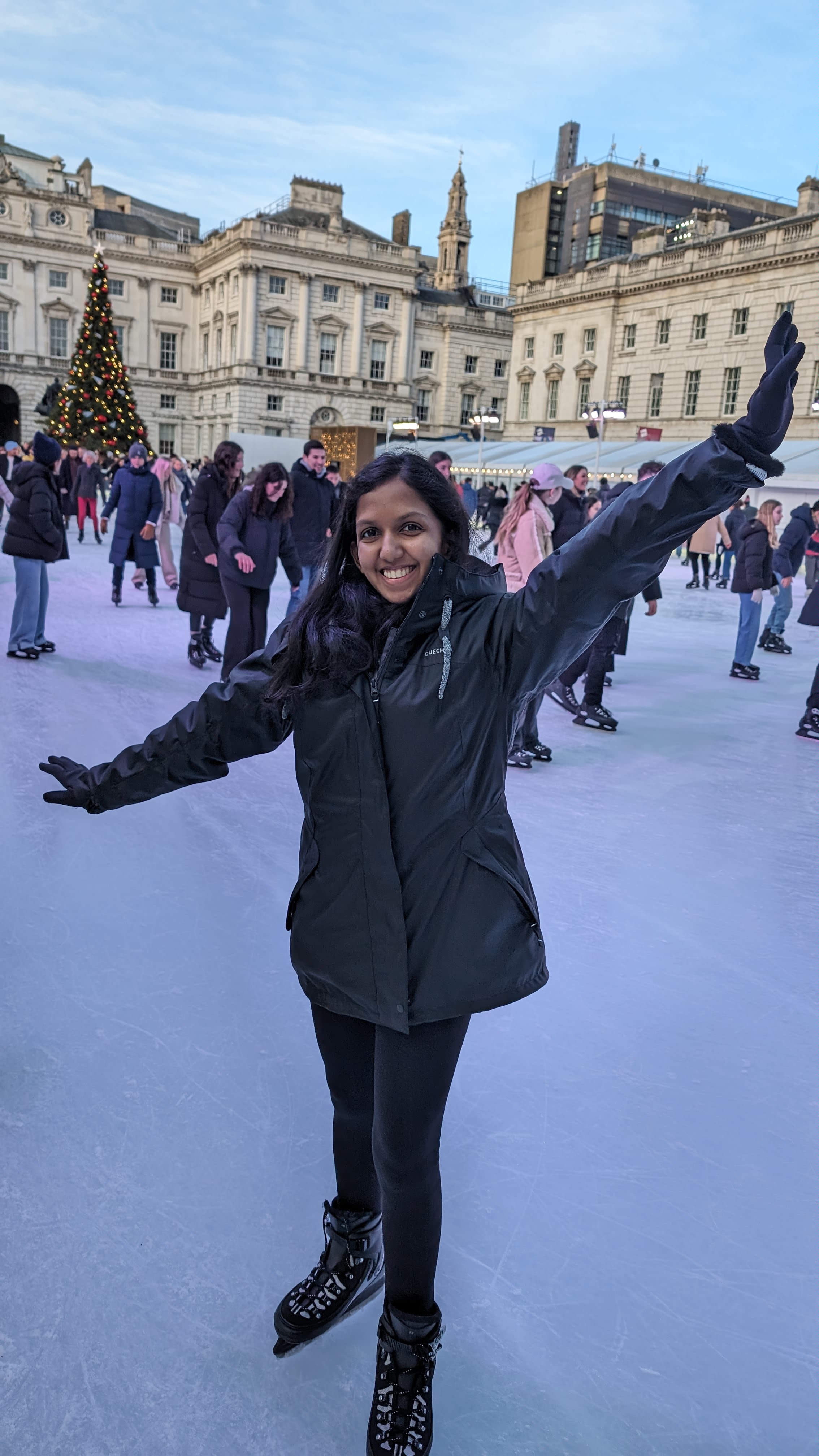 Vanya posing with her arms up in the air standing on an ice rink in winter