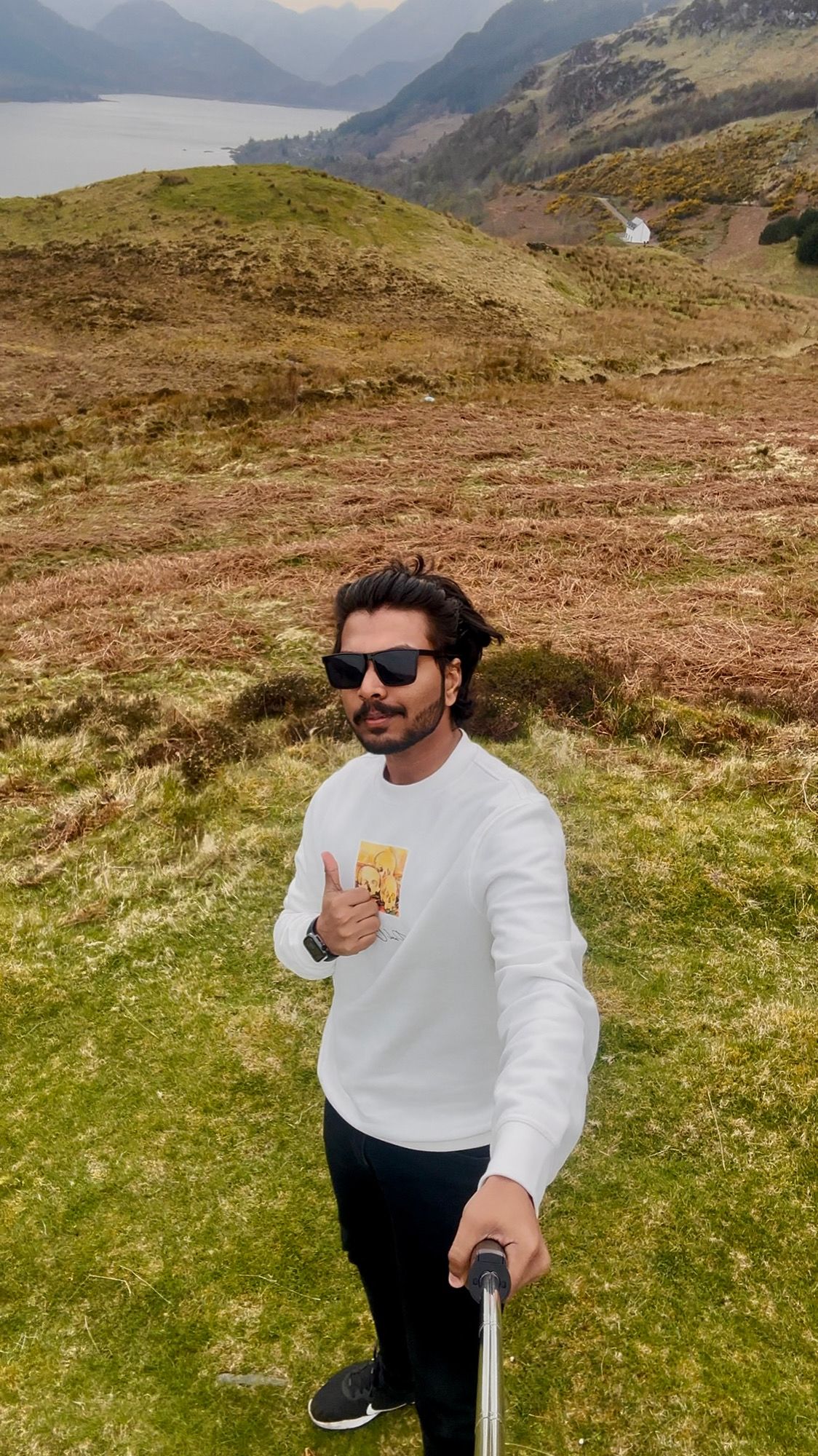 Vijay standing on a mountain giving a thumbs up