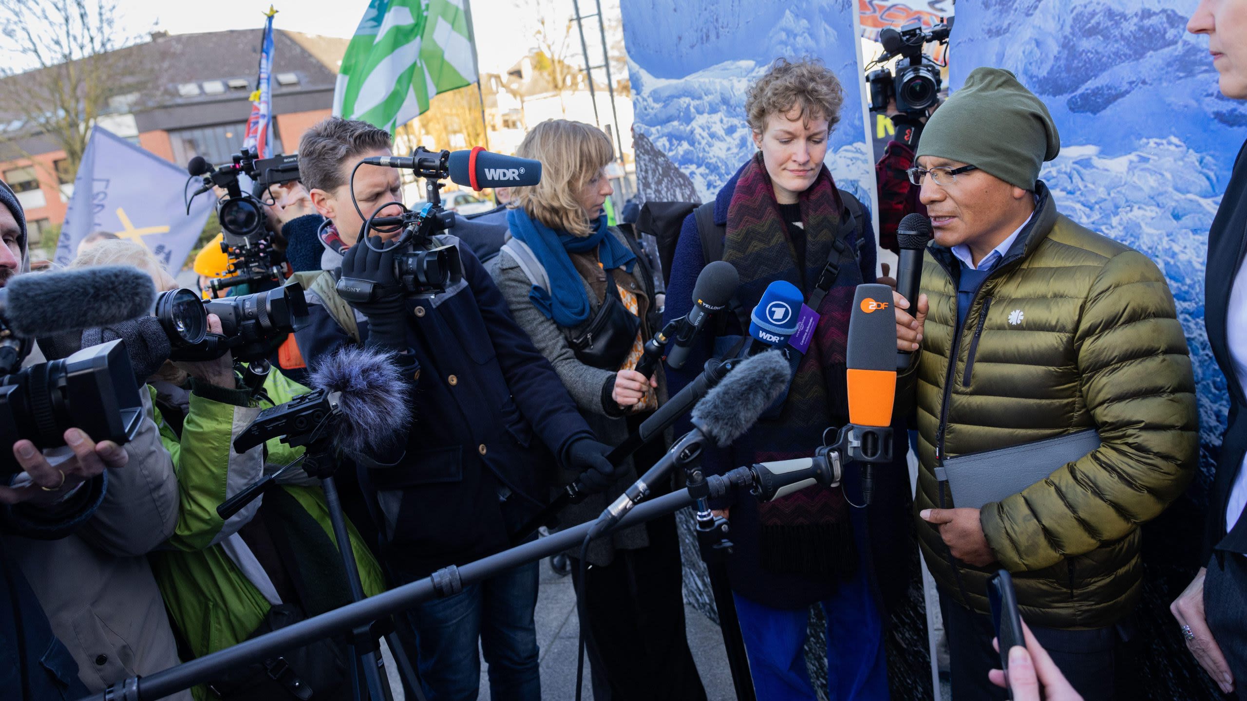 Saúl Luciano Lliuya speaking into a collection of microphones held by a crowd of journalists