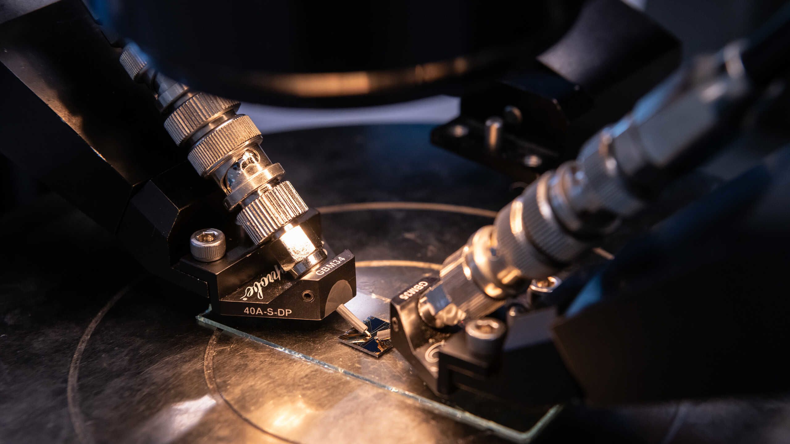 Two probes positioned above a silicon chip on a microscope slide.