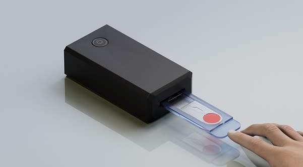 A hand prepares to load a cartridge into a blood cell reader.