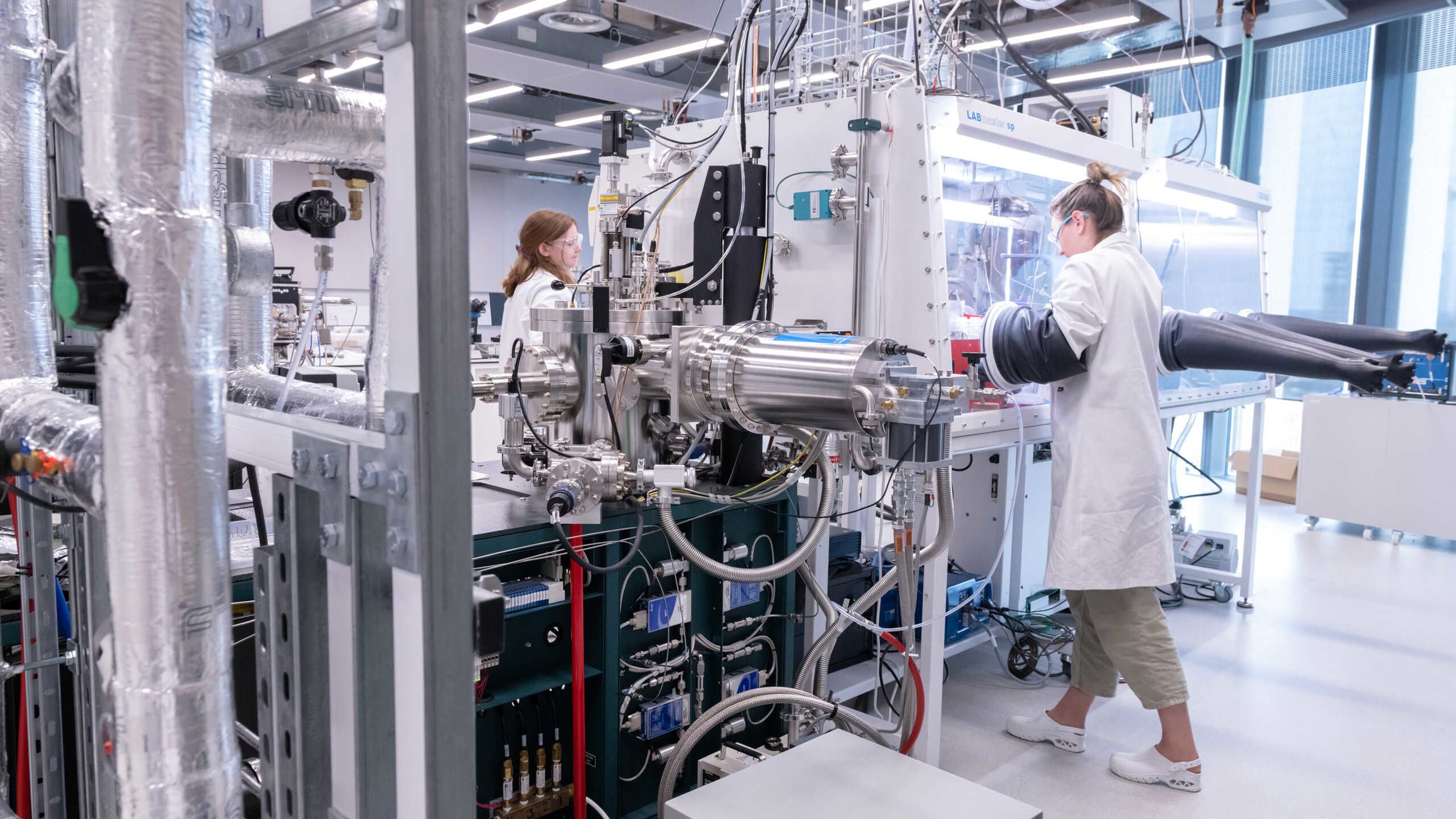 Two researchers work at a glove box
