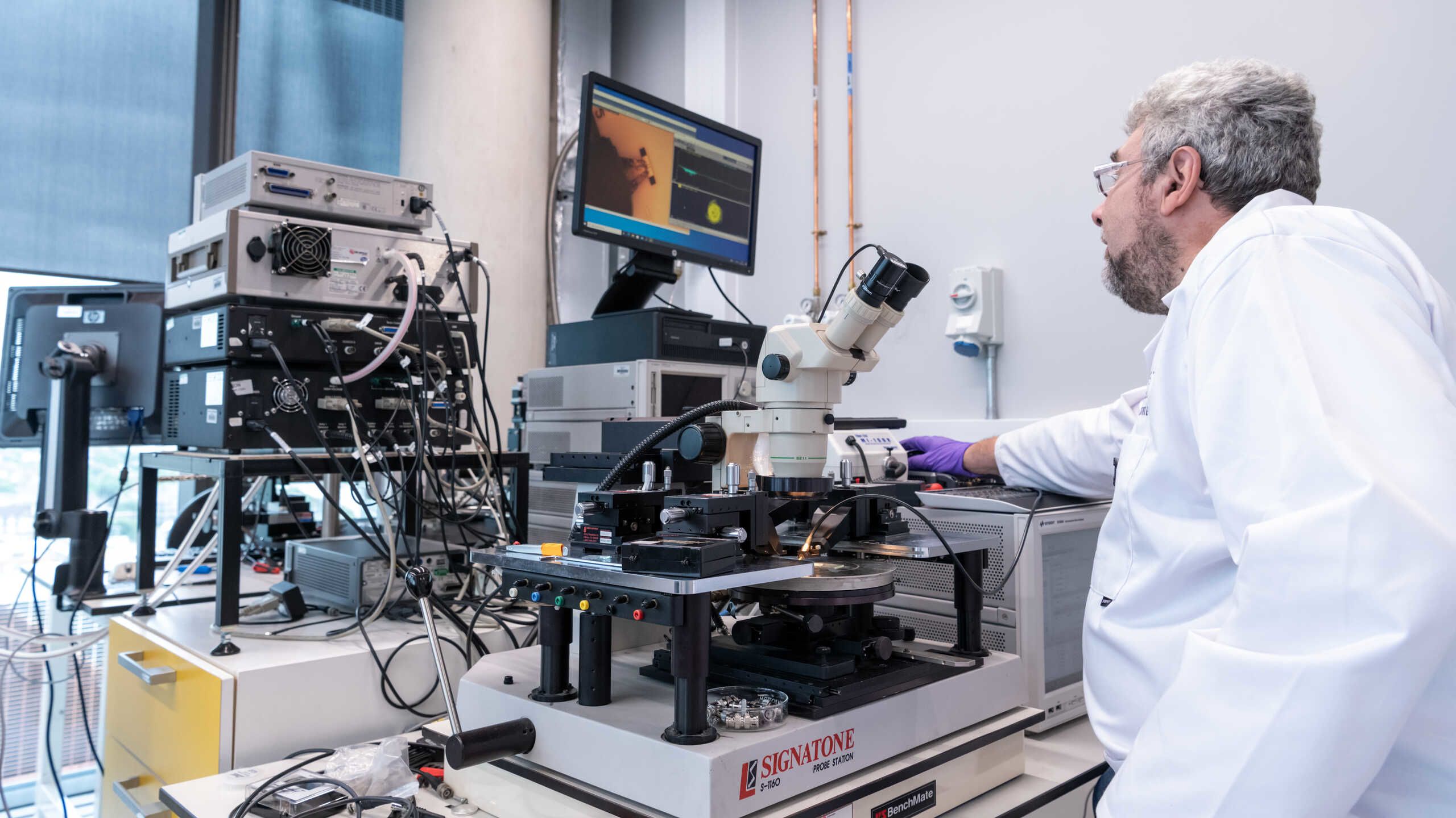 A researcher uses a complex microscope.