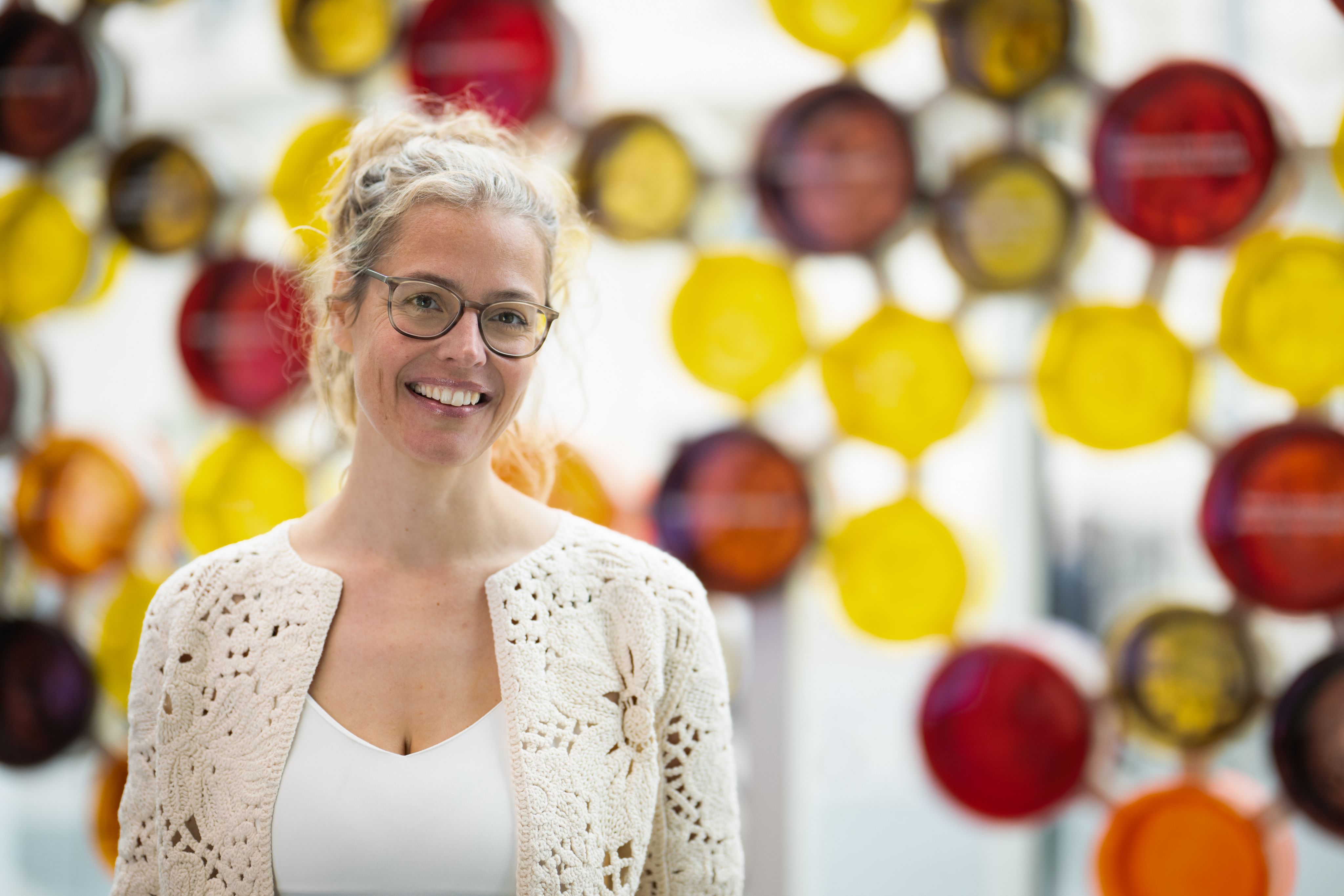 Close up portrait of Sabine in front of the molecule art piece.