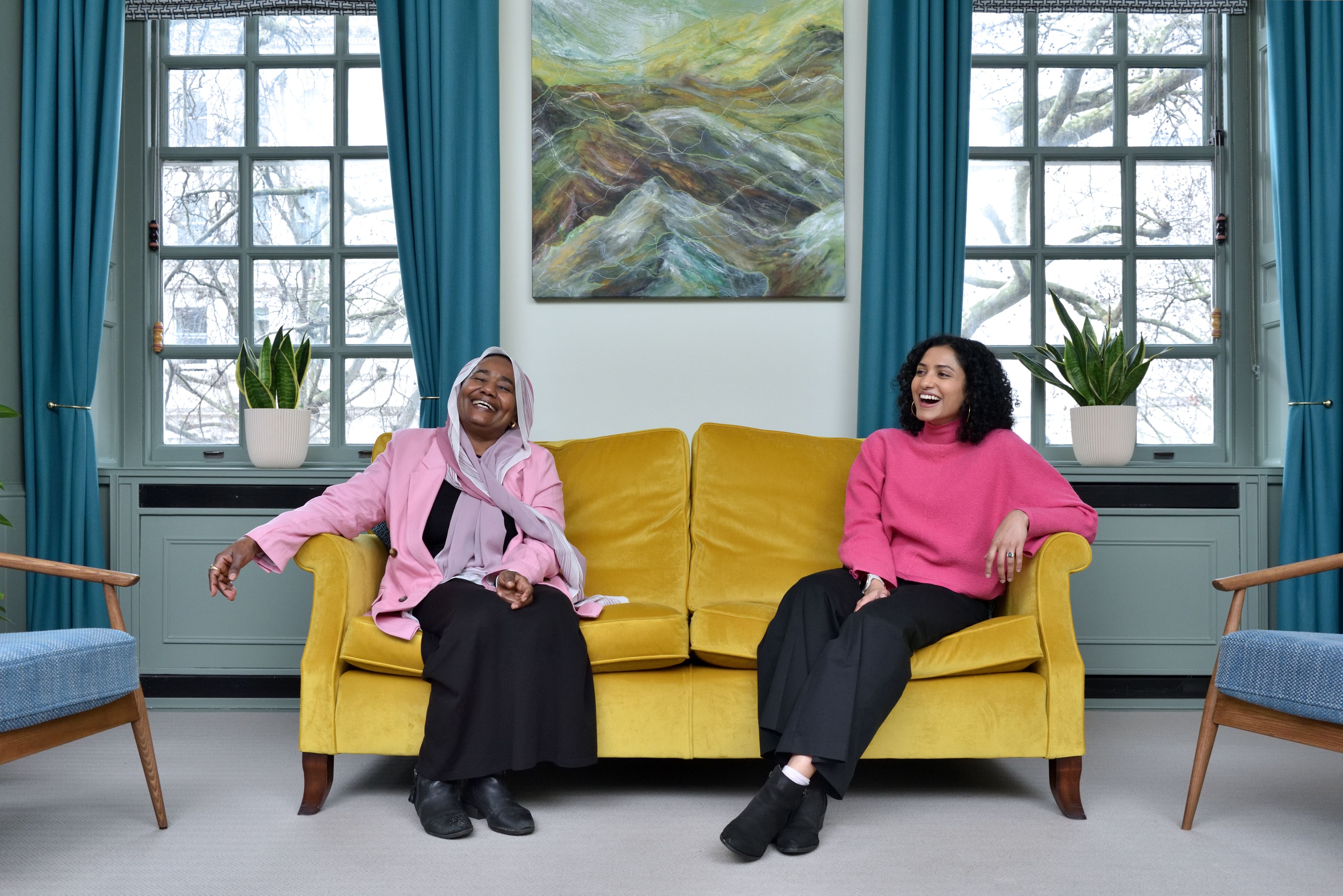 Sarindi Aryasinghe and Phayza Fudlalla sitting at opposite ends of a cough both laughing