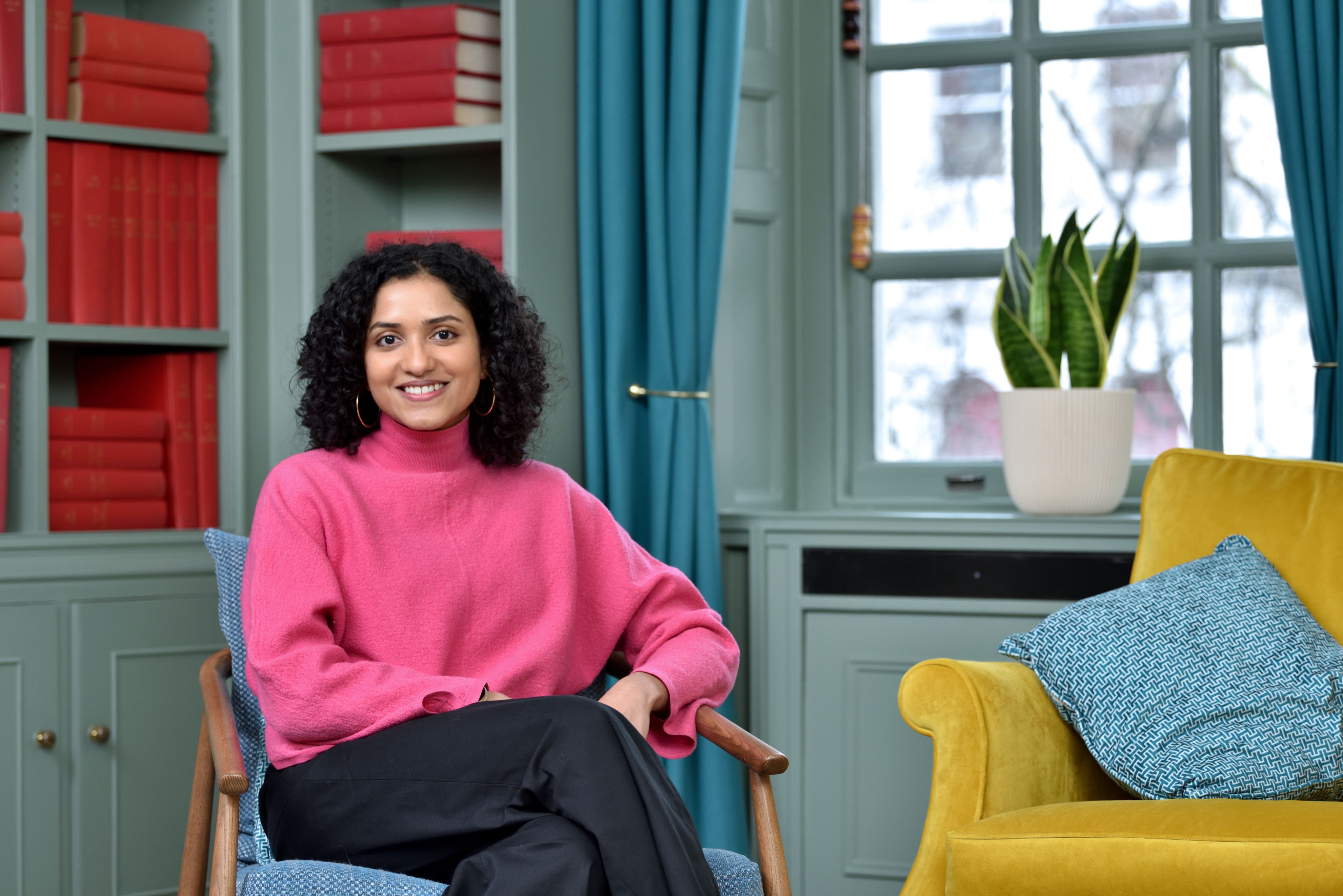 Sarindi smiling at the camera while sitting on a chair.