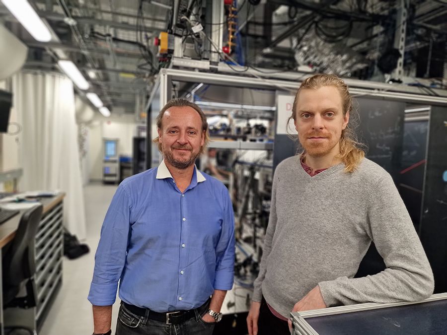 Two scientists stand in front of the AION experiment at Imperial