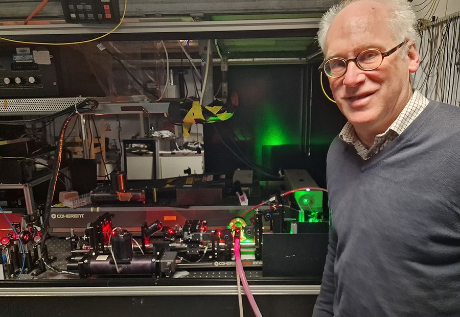 An Imeprial scientist stands in front of a tabletop experiment