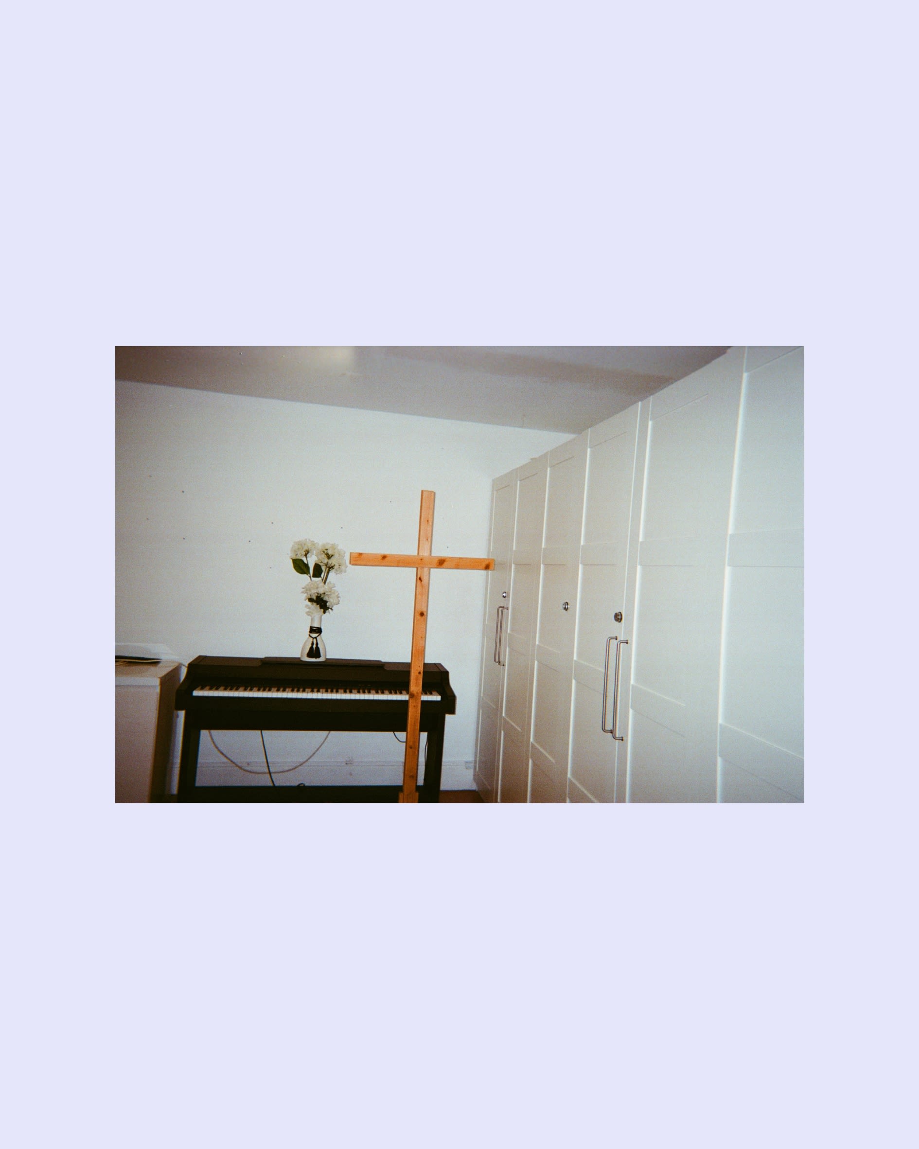 A piano with a vase of flowers on top of it and a wooden cross in front of it.