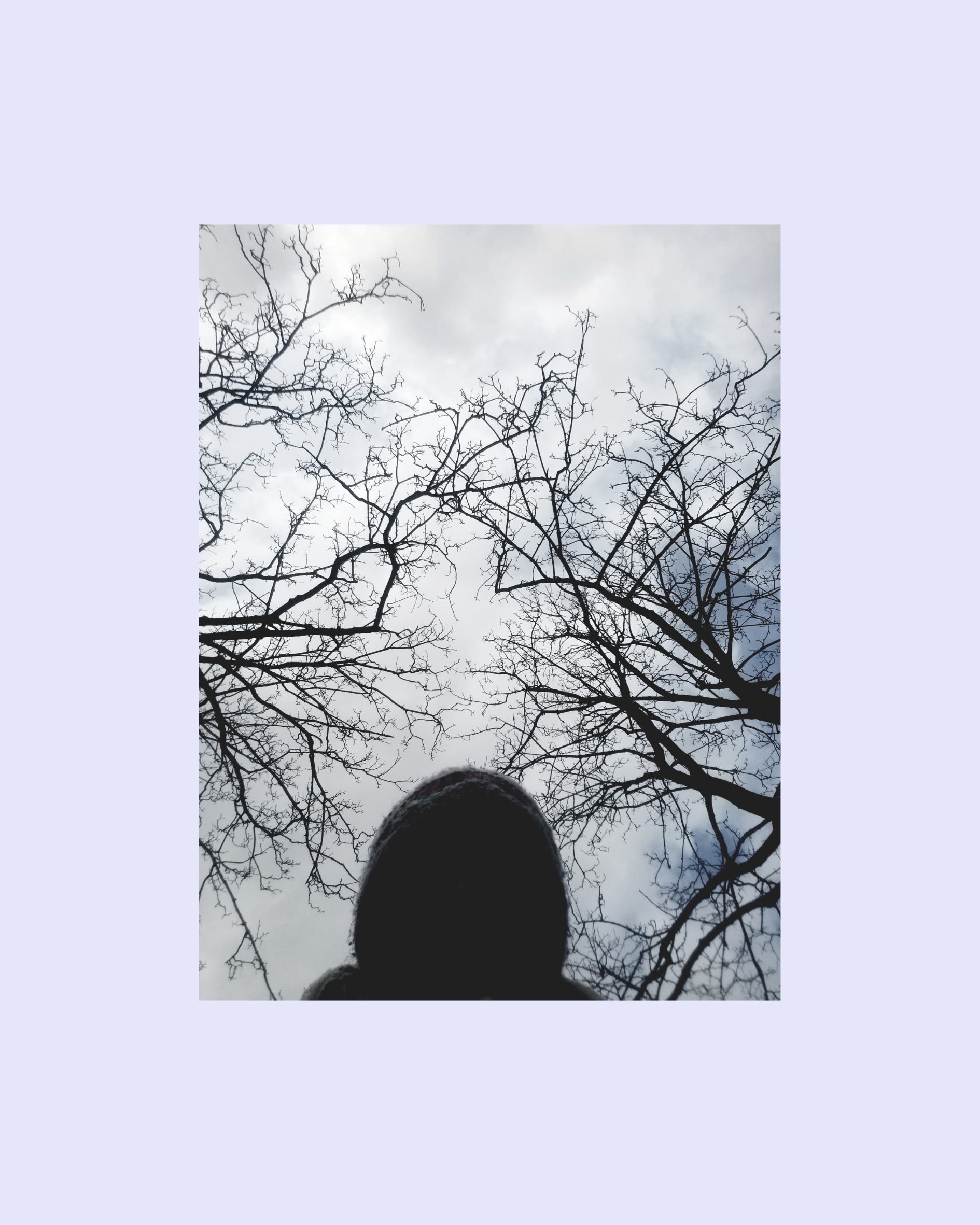 The shadow of a woman's head with clouds and trees in the background.