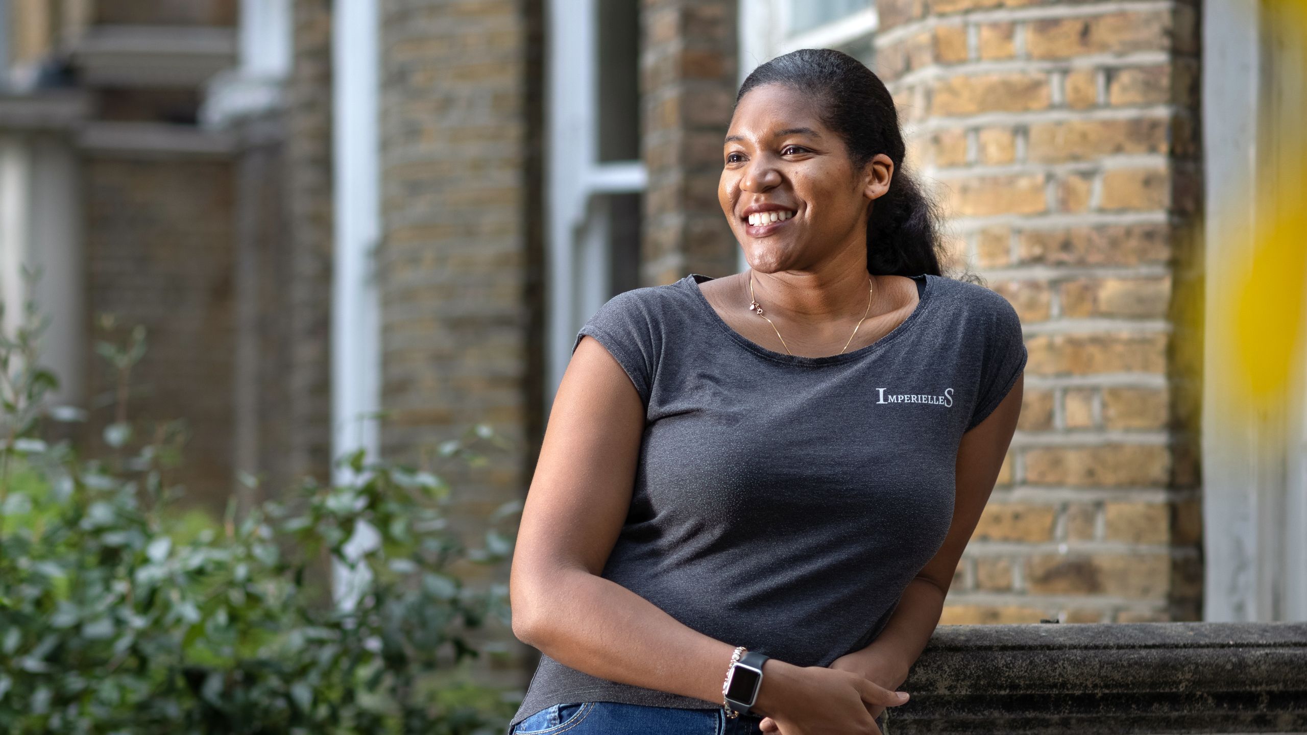 Alicia Gayle, leans against the entrance to her house