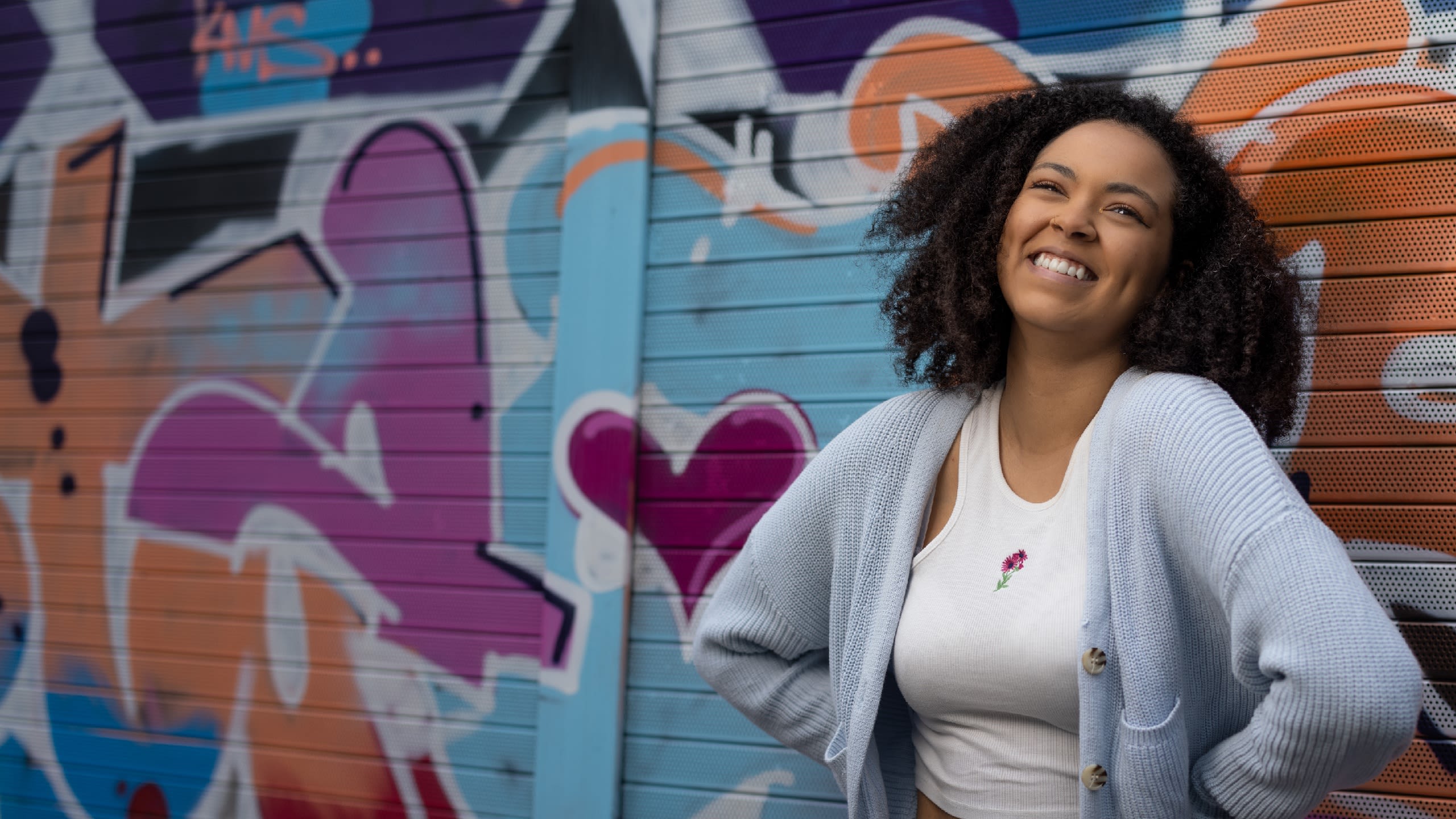 Hollie standing against a wall of street art