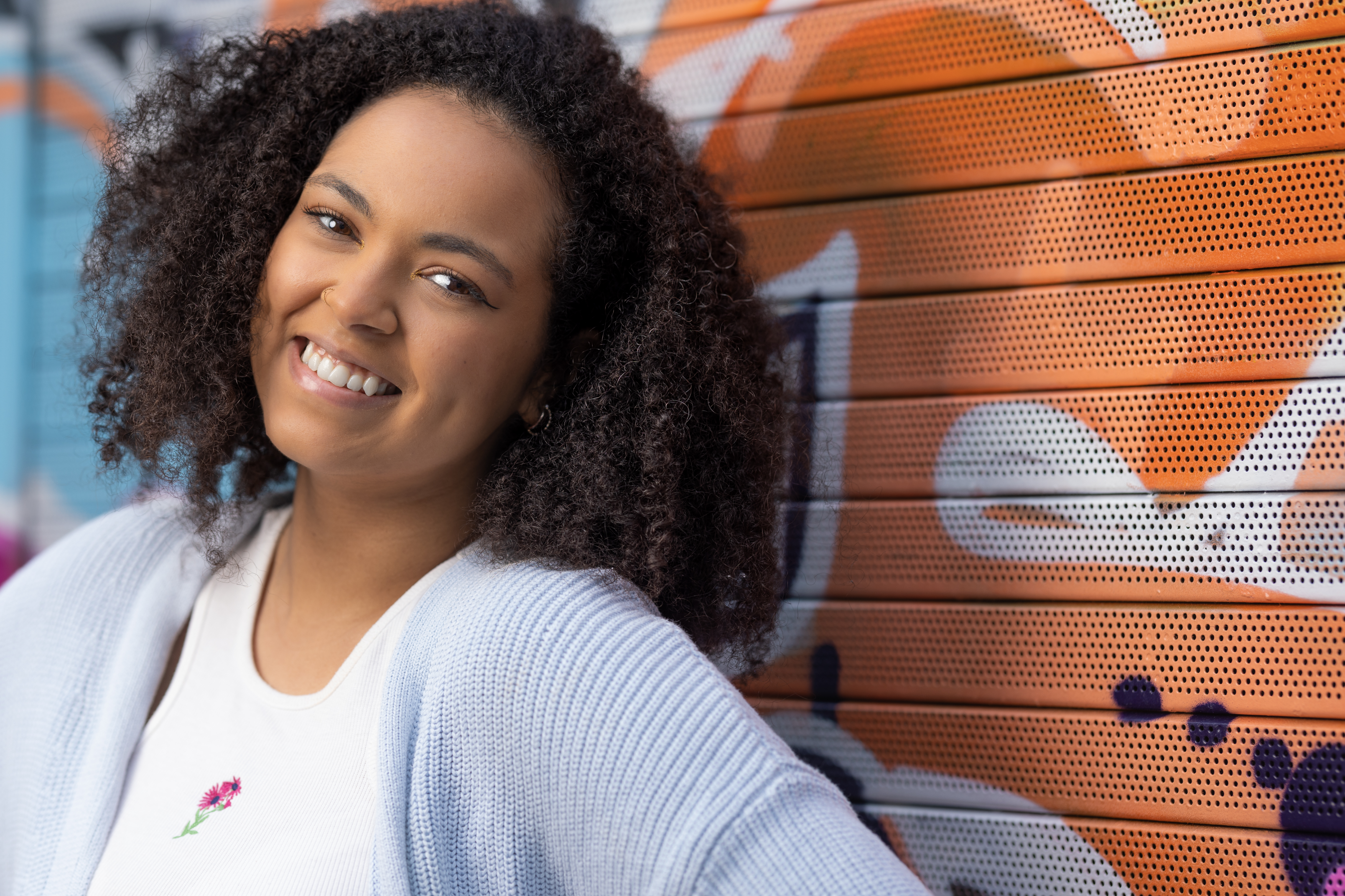 Hollie smiling at the camera against a bright graffiti background