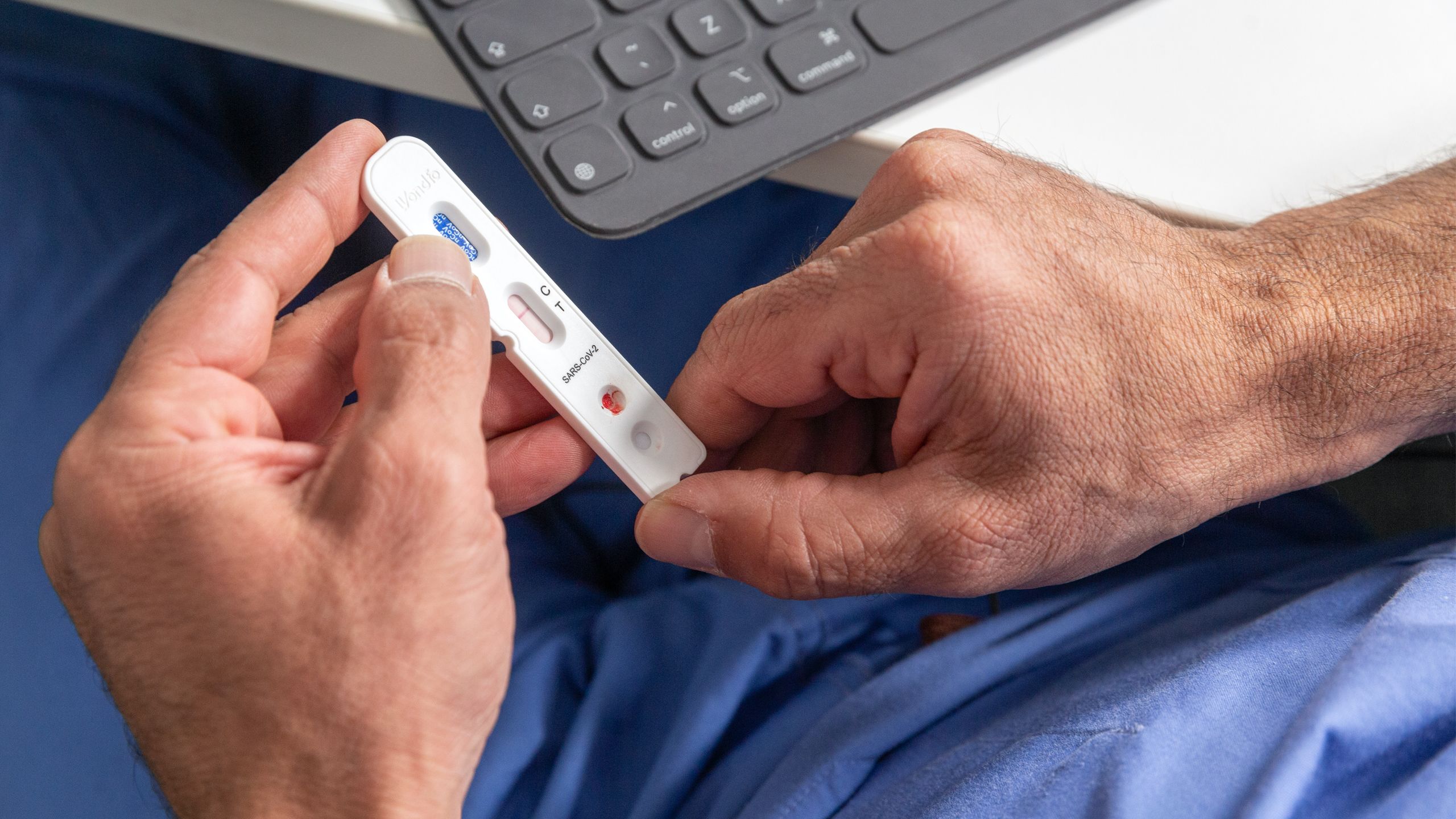 Man holding coronavirus testing stick used in REACT study