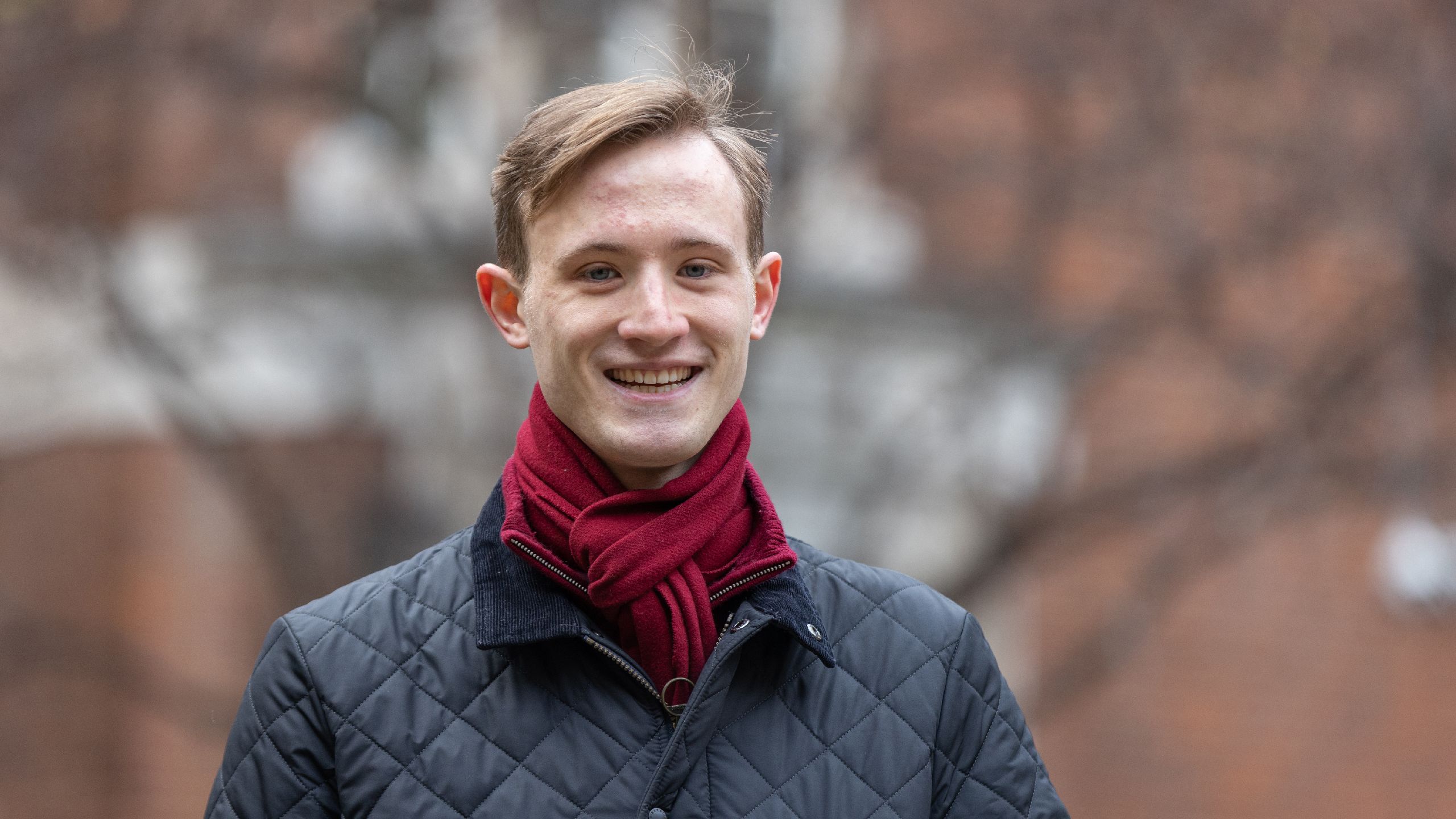 Michael smiling outdoors in a coat and scarf