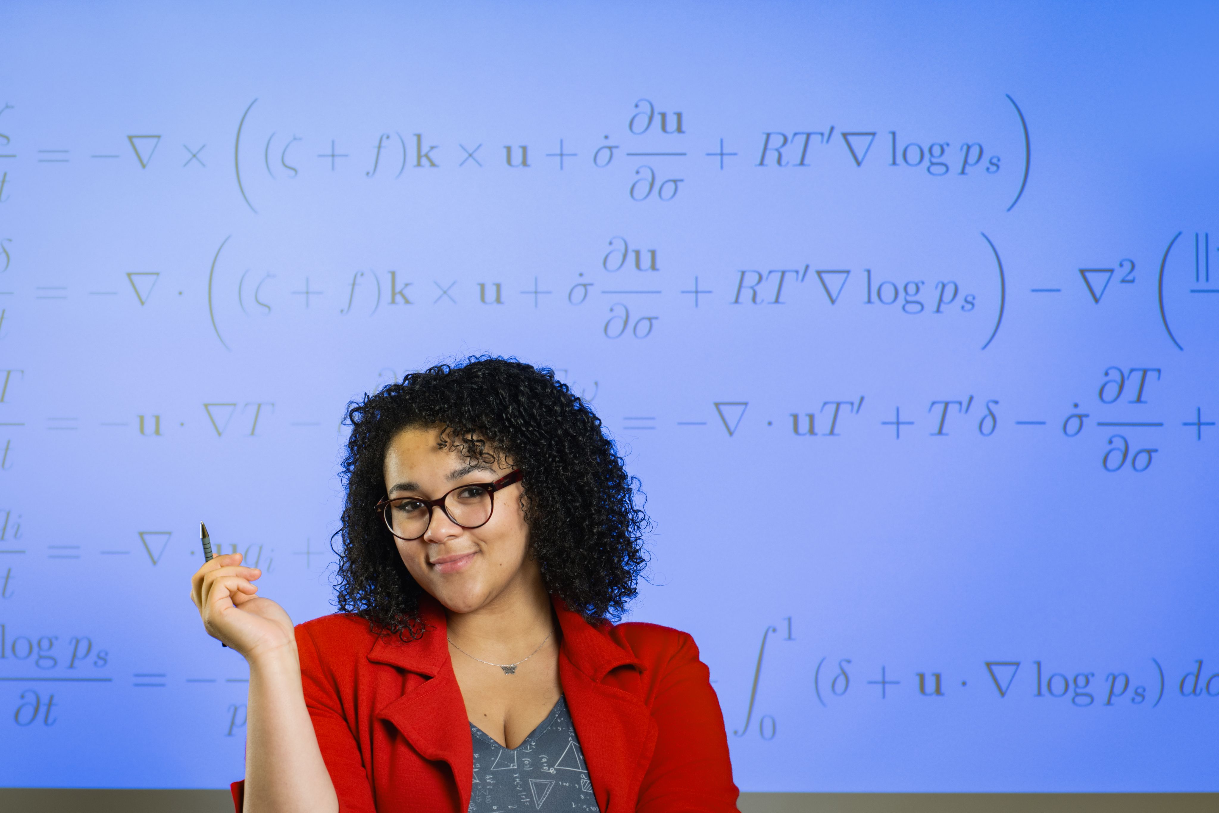 Vanessa smiling in front of a screen with maths equations.