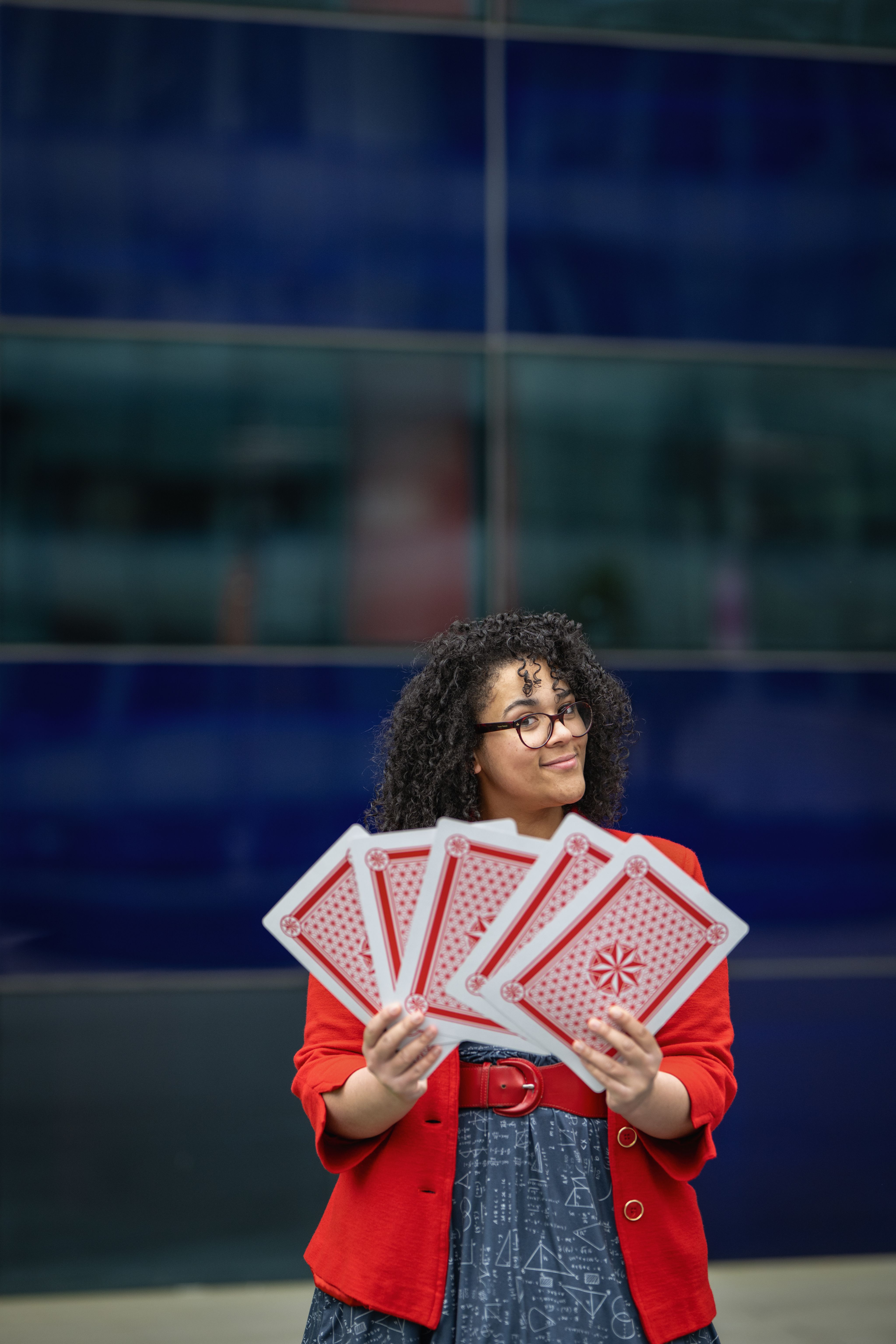 Vanessa smiling while holding her large playing cards in a uniformed hand.