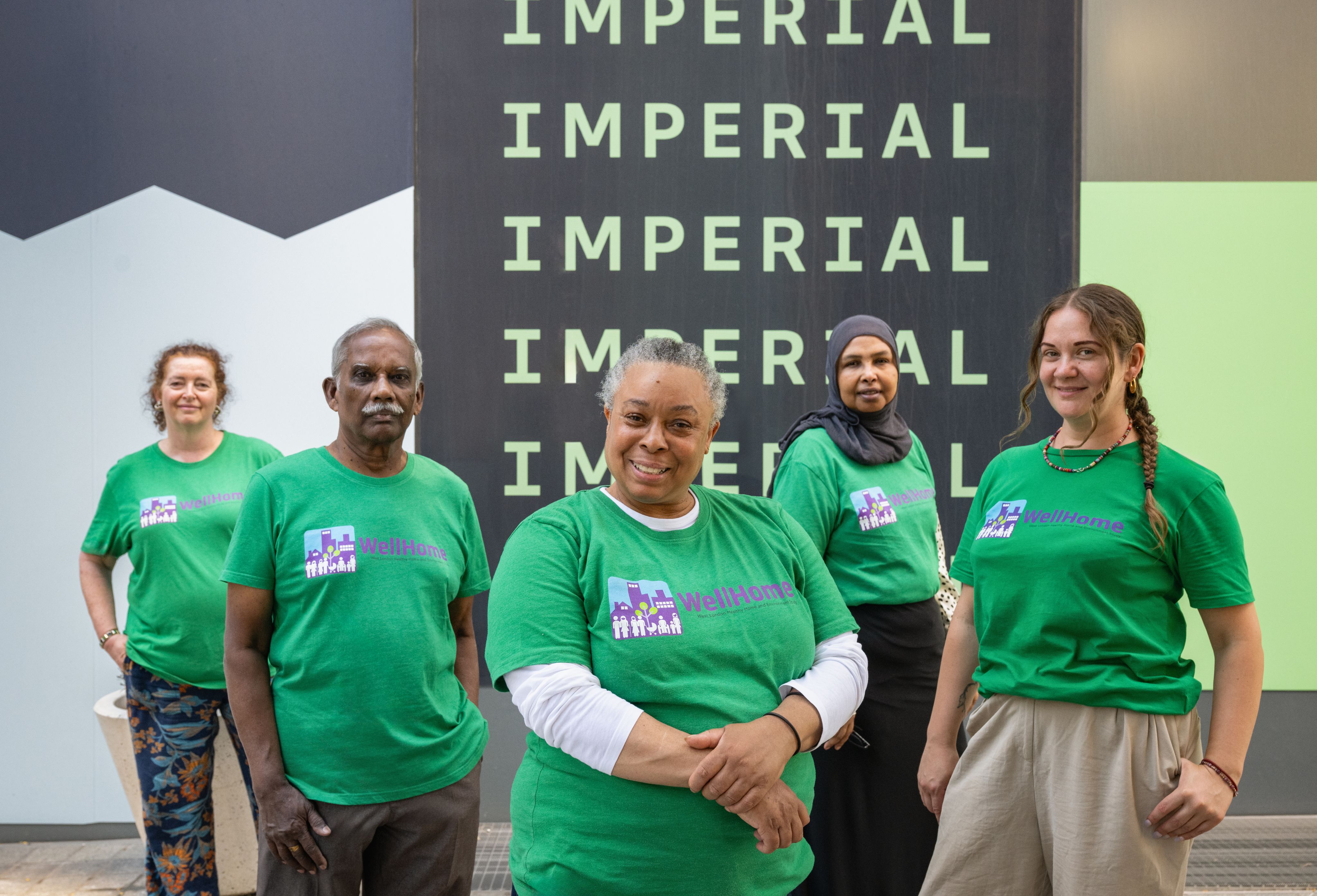 The WellHome Ambassadors stand in a group in front of Imperial signage.
