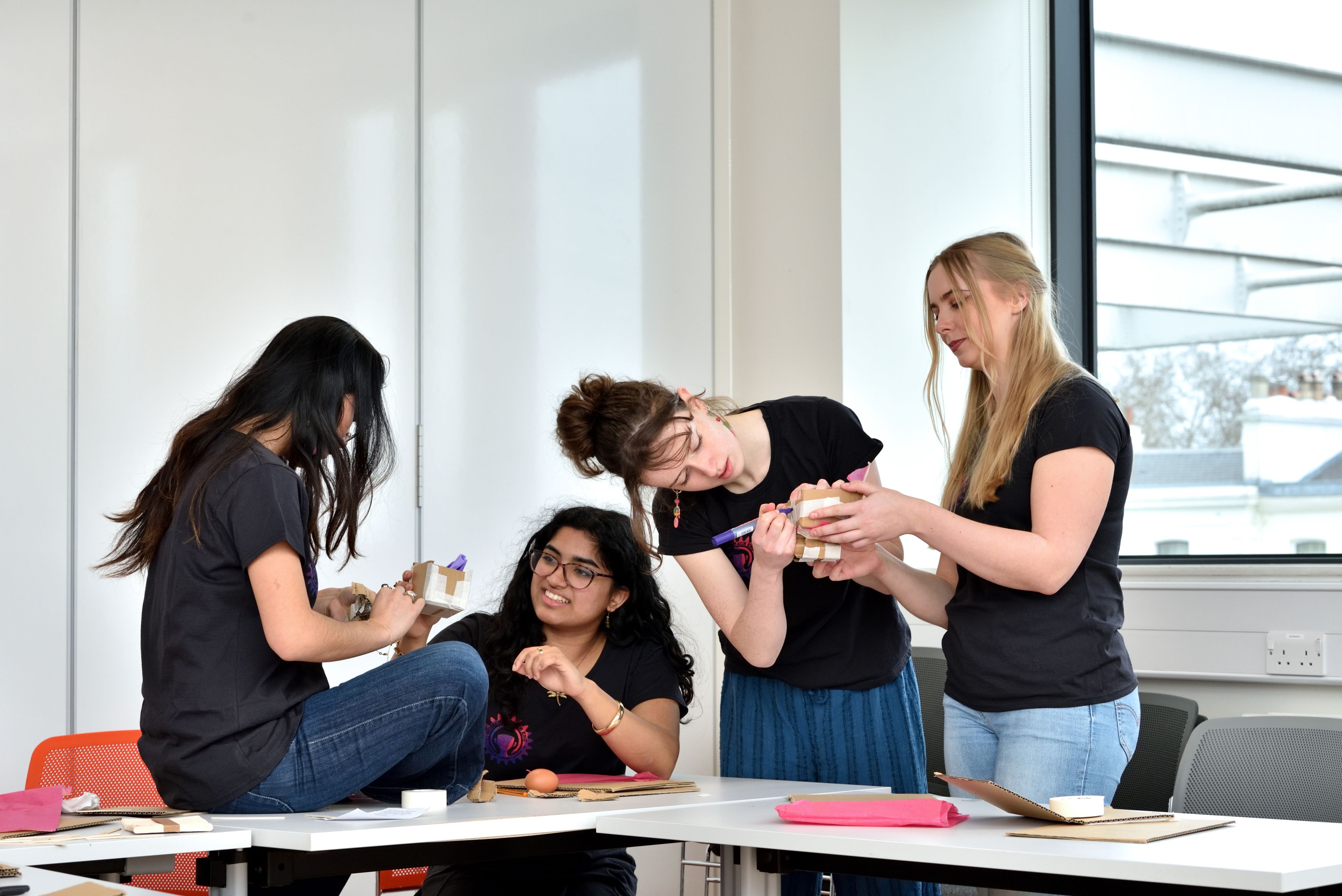 Four members of the society focused on crafting a cardboard box to protext eggs in the egg-crumple zone workshop activity.
