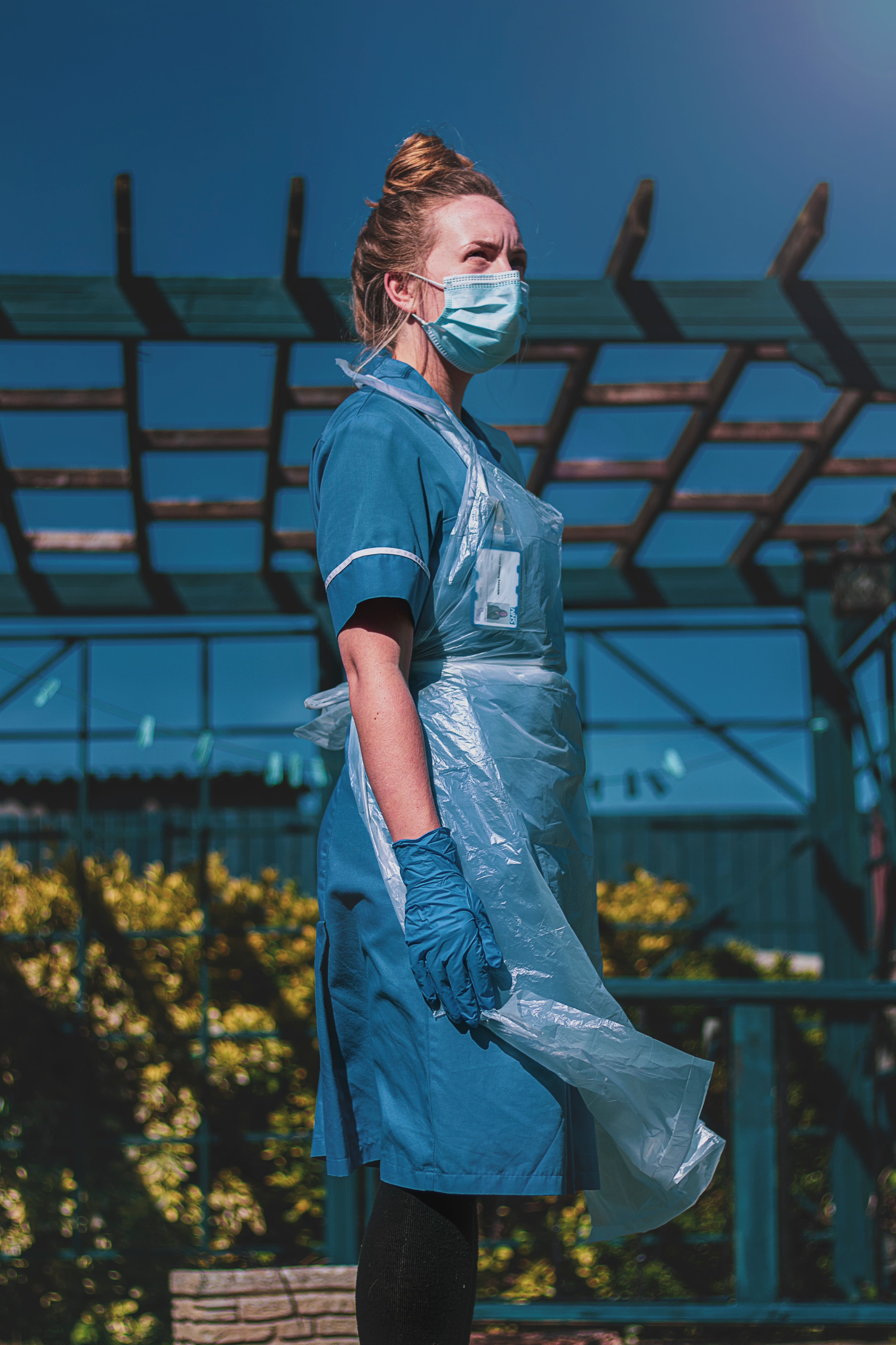 woman in a blue healthcare uniform standing on yellow flower field during daytime